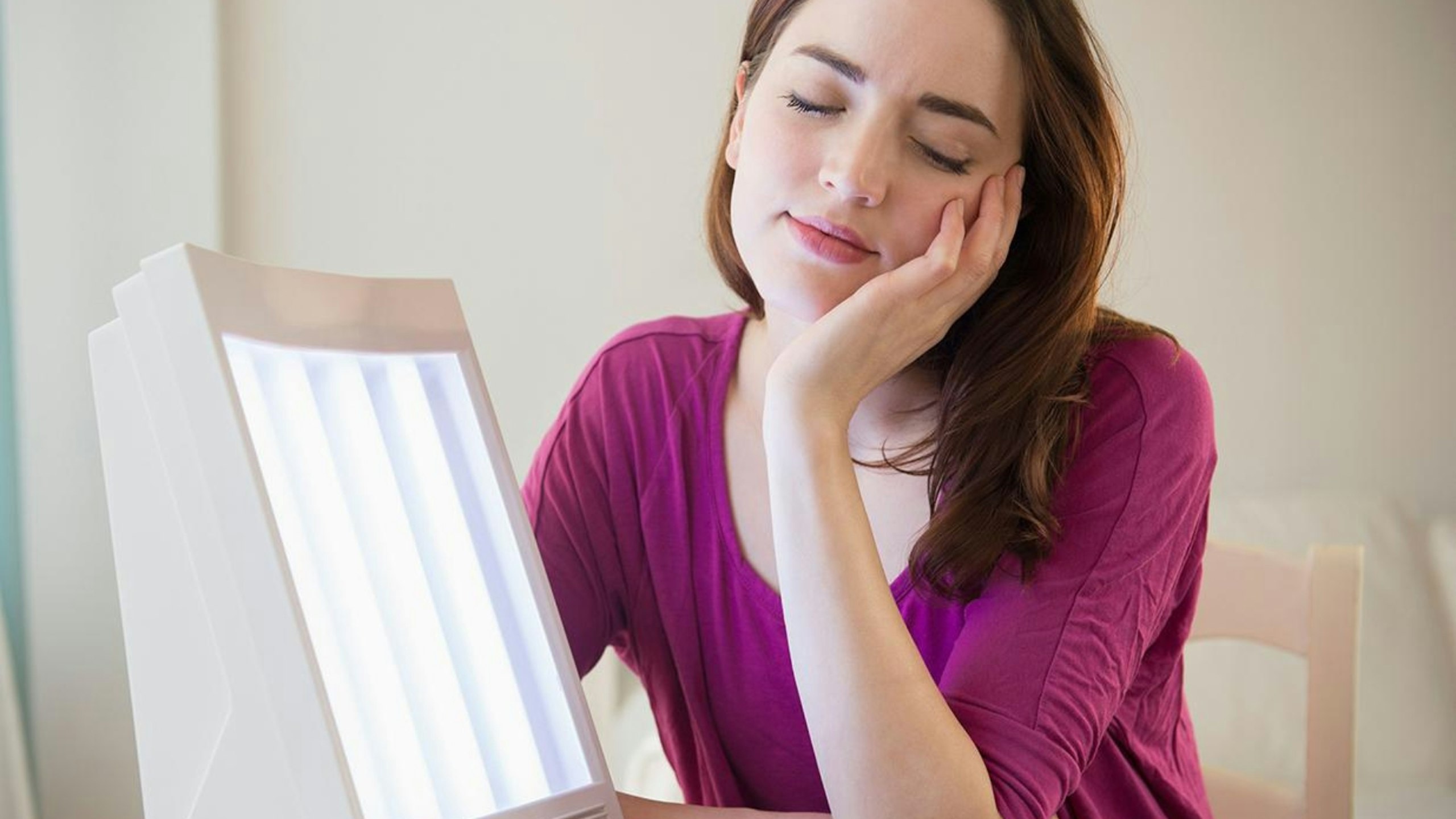 Woman sitting by light therapy box