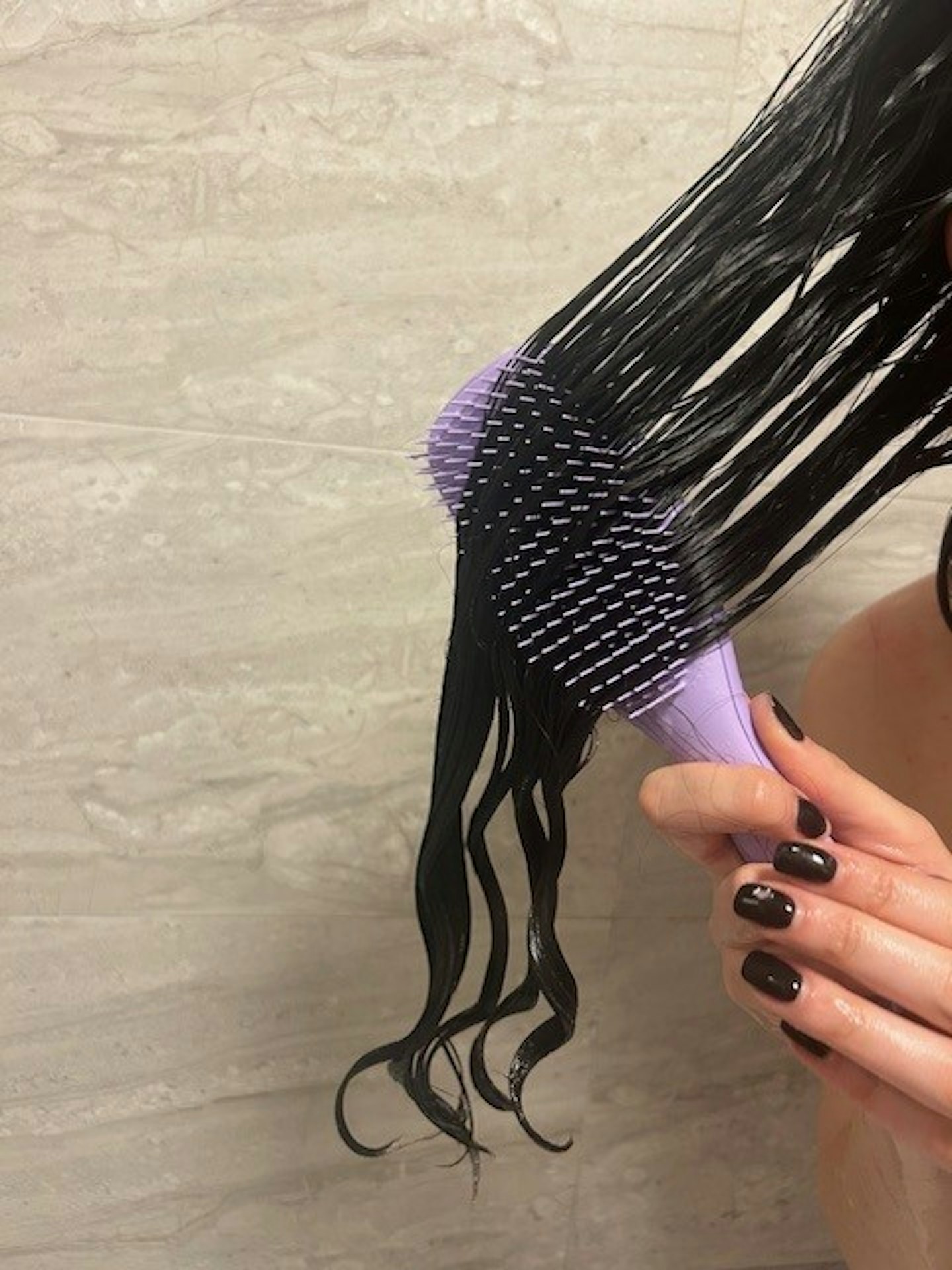 A woman detangling hair in the shower