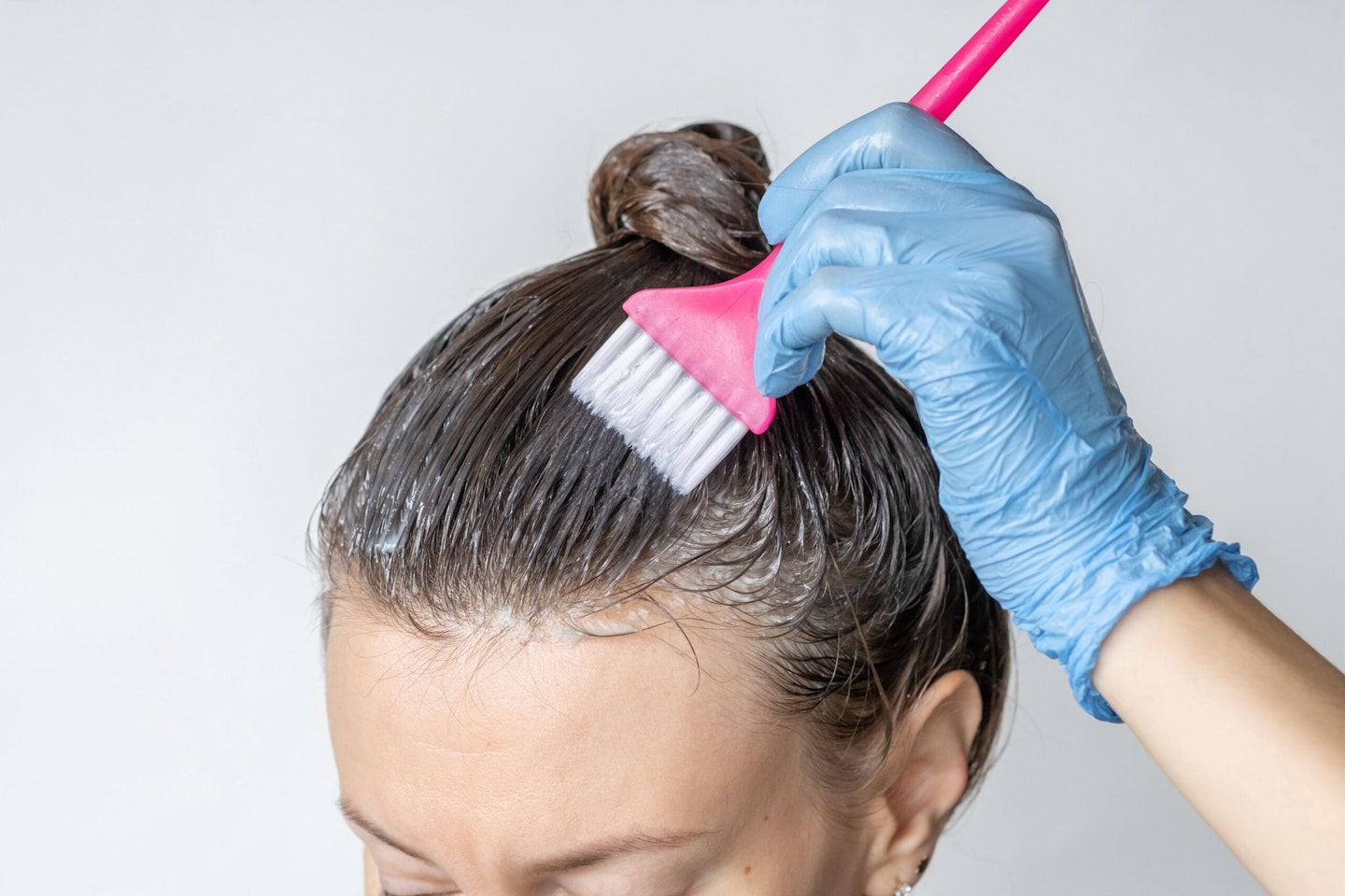 Close-up of a woman's heClose-up of a woman's head in the process of hair coloring on a white backgr