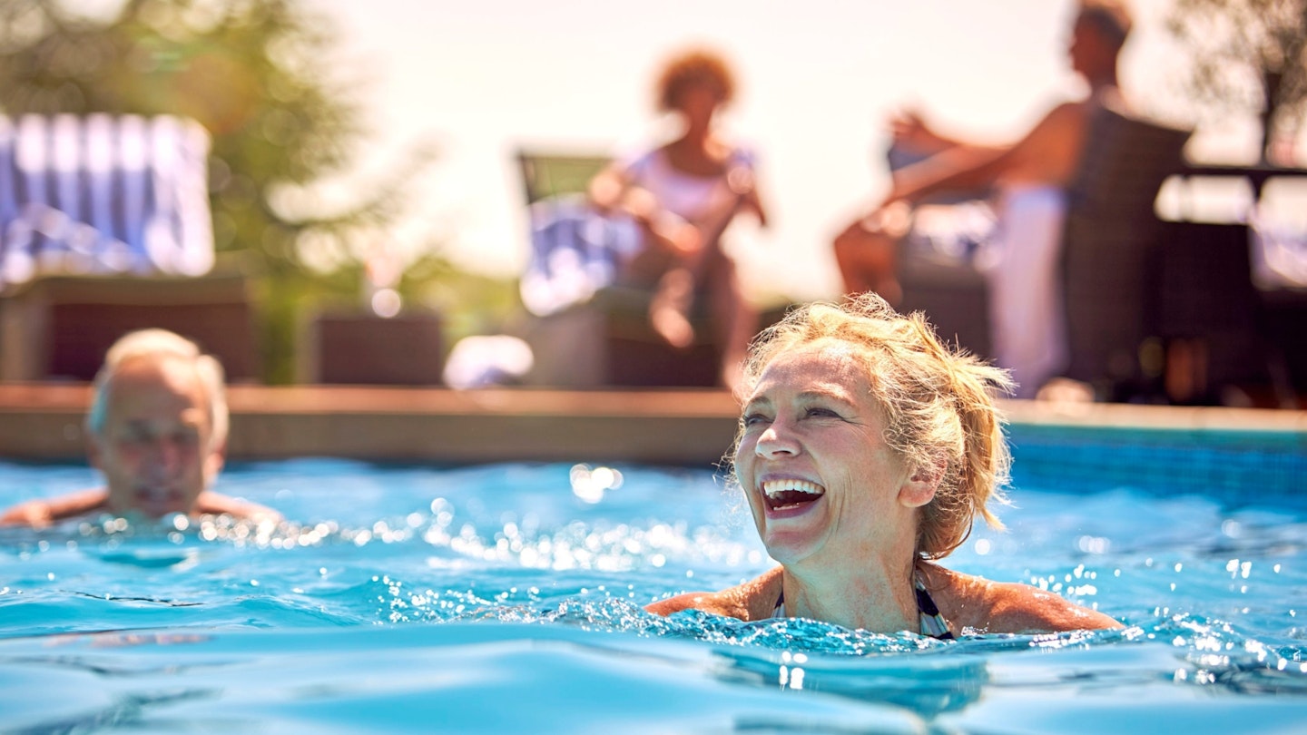 Retired Senior Couple Relaxing In Swimming Pool On Summer Vacation