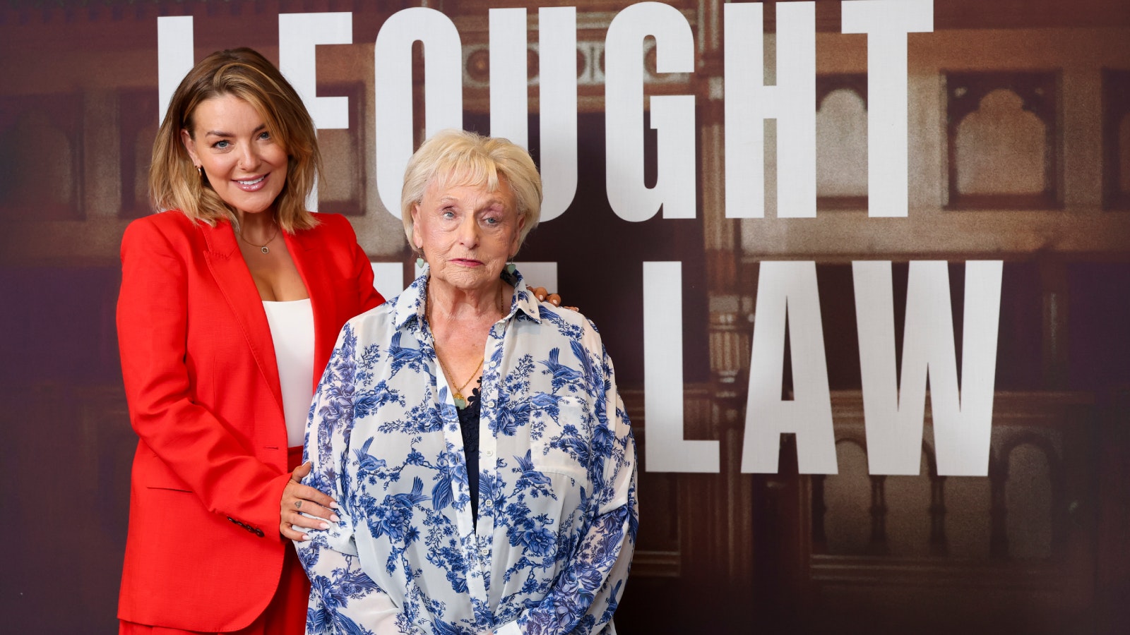 Sheridan Smith and Ann Ming behind a sign for I Fought the Law