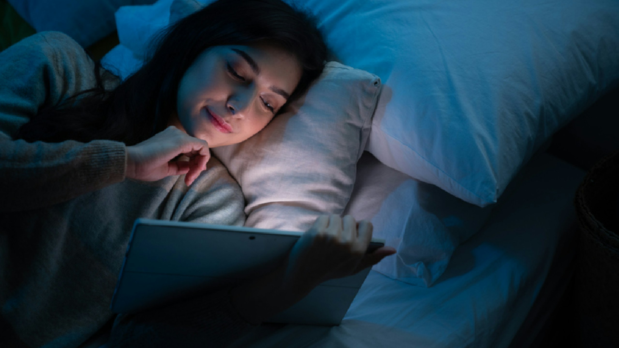 woman in bed reading laptop
