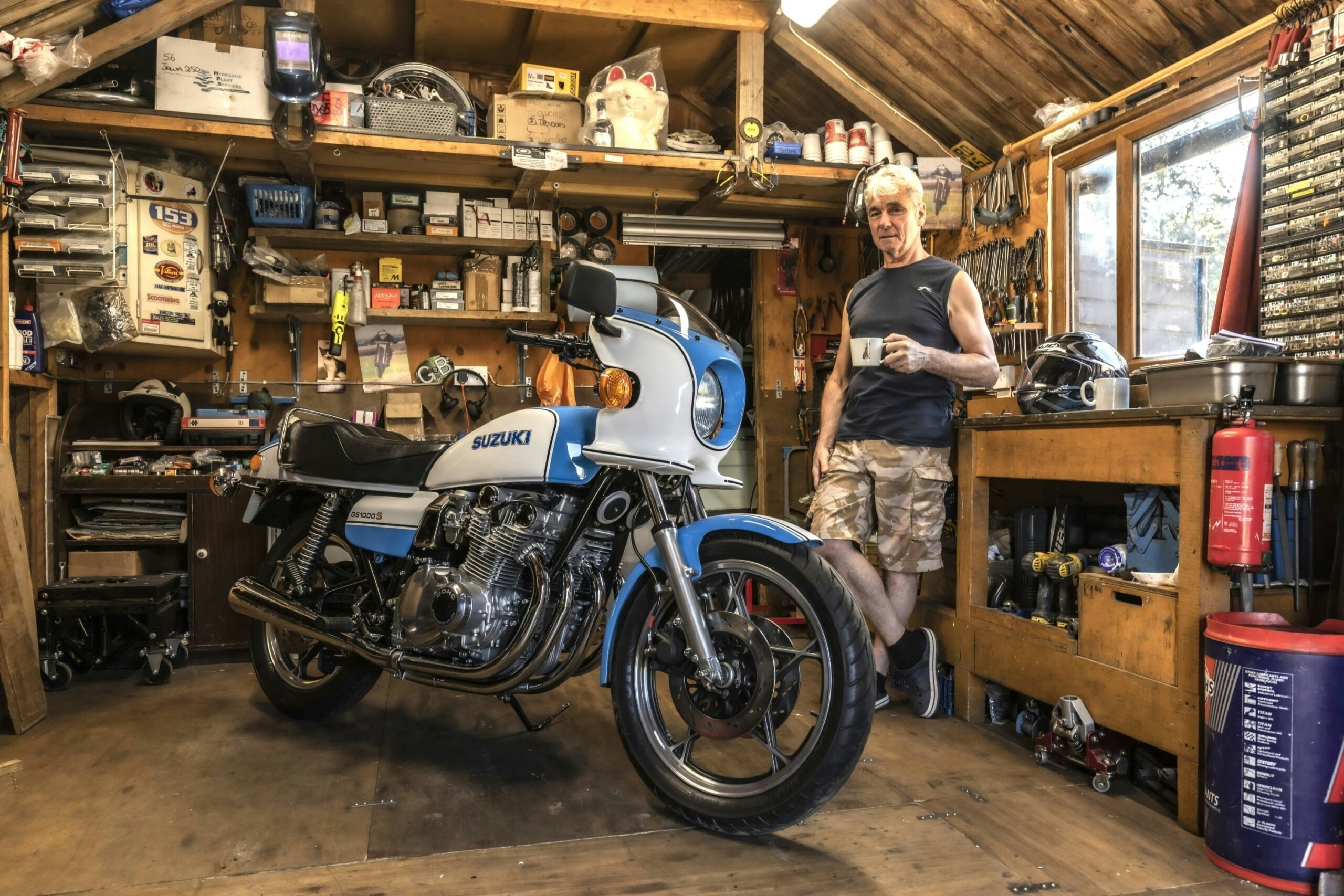 Suzuki GS1000S parked inside a home workshop with tools and workbench in the background
