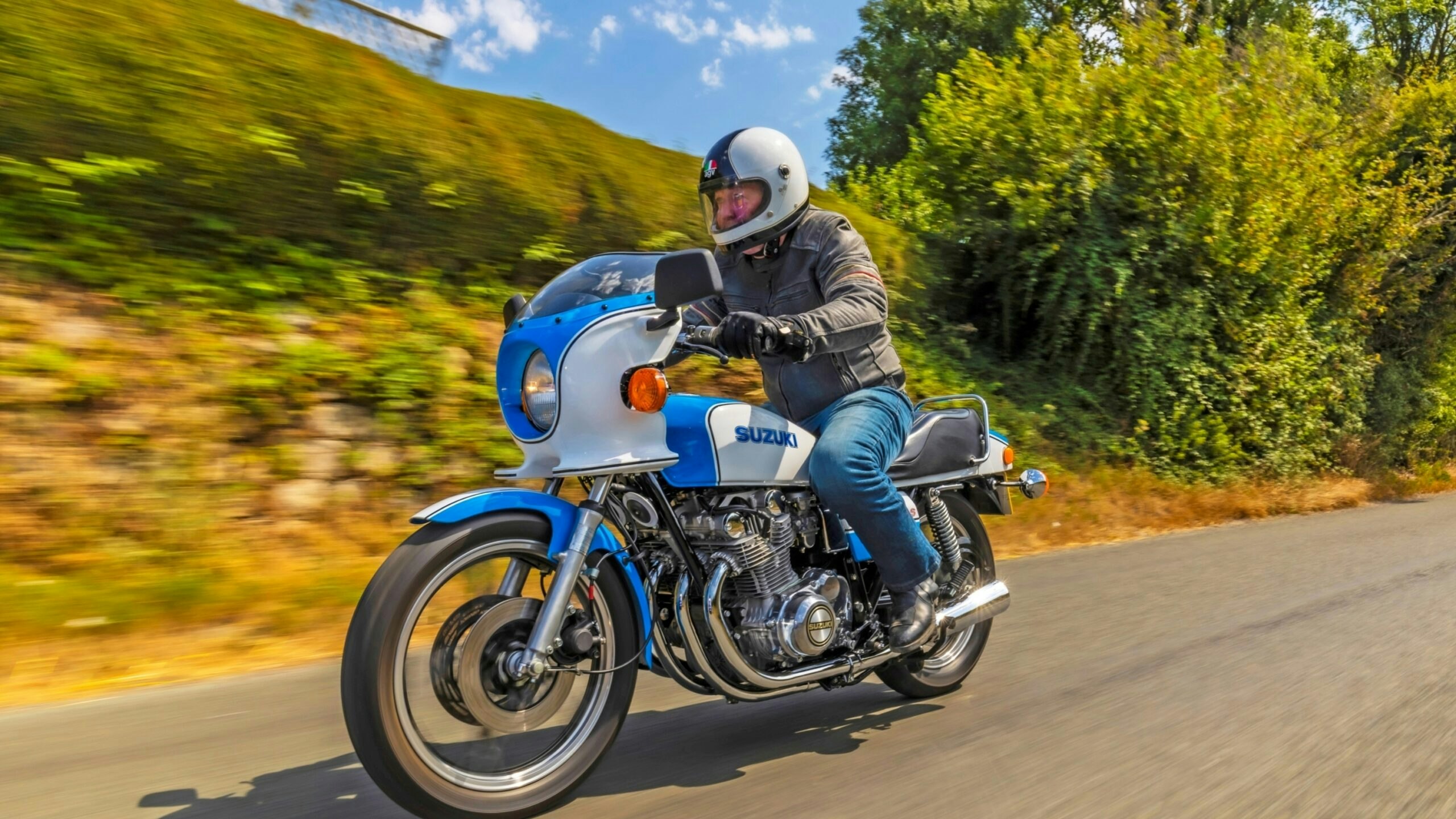Front three-quarter view of the Suzuki GS1000S being ridden along a country road