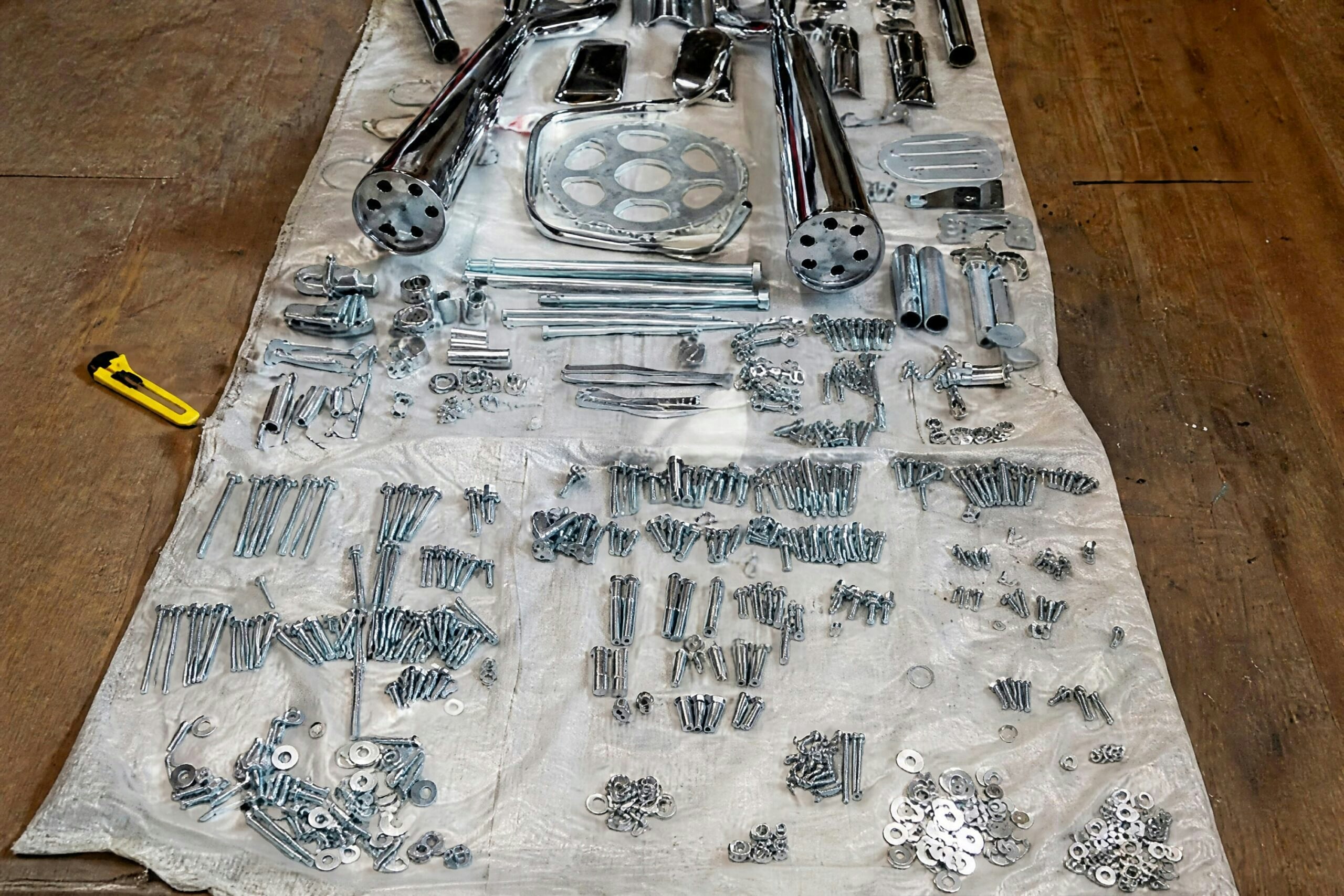Chrome-plated Suzuki GS1000S parts and fasteners laid out during a motorcycle restoration project