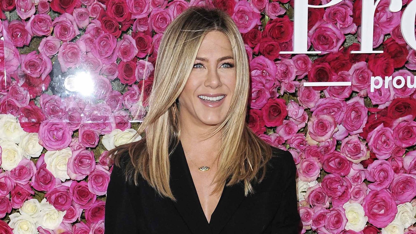 jennifer aniston smiling pink flowers in the background