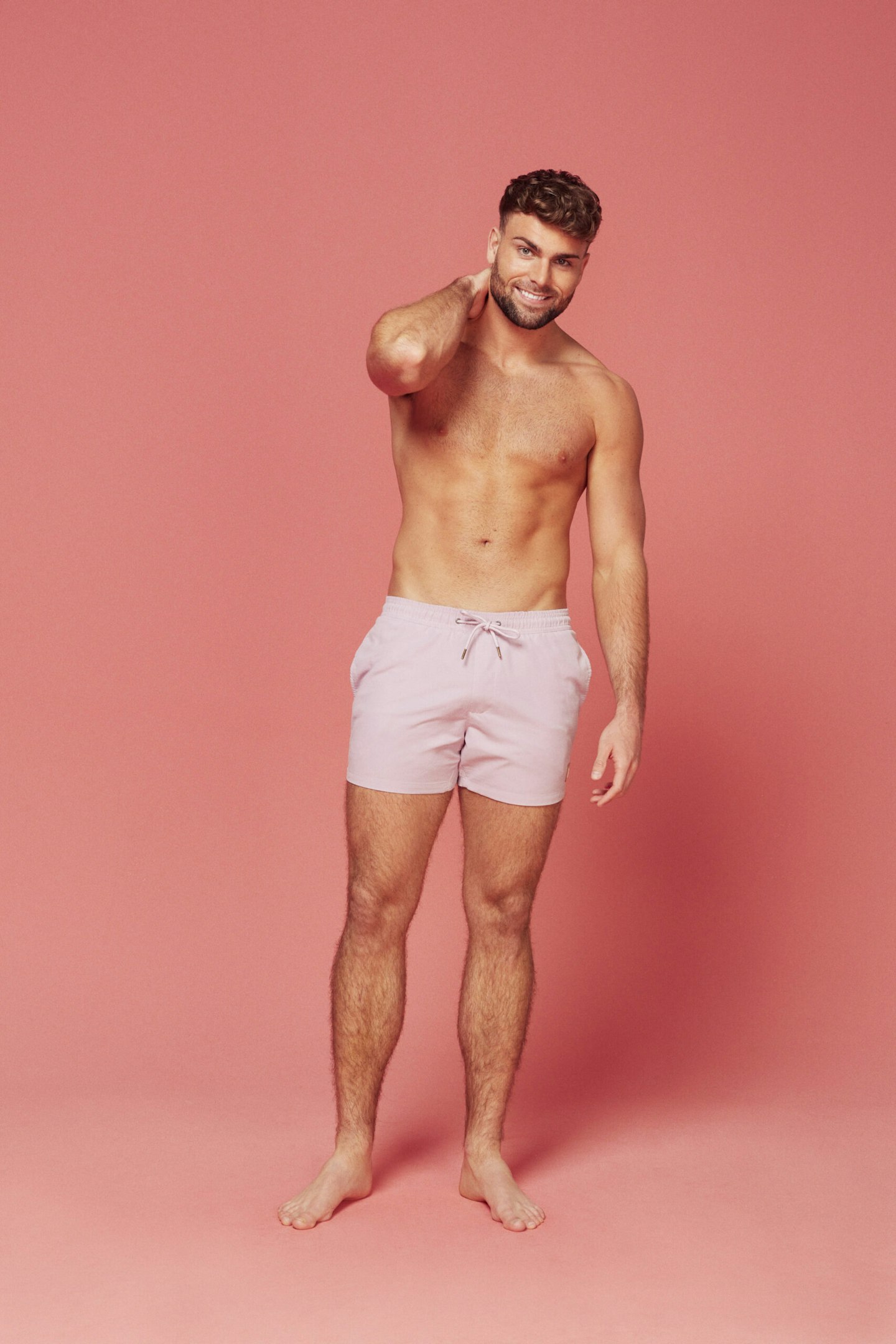 Love Island's Tom Clare posing in front of a pink background