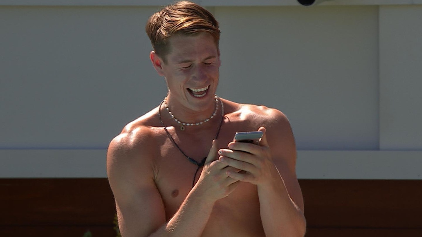 Will Young in the Love Island villa holding his phone