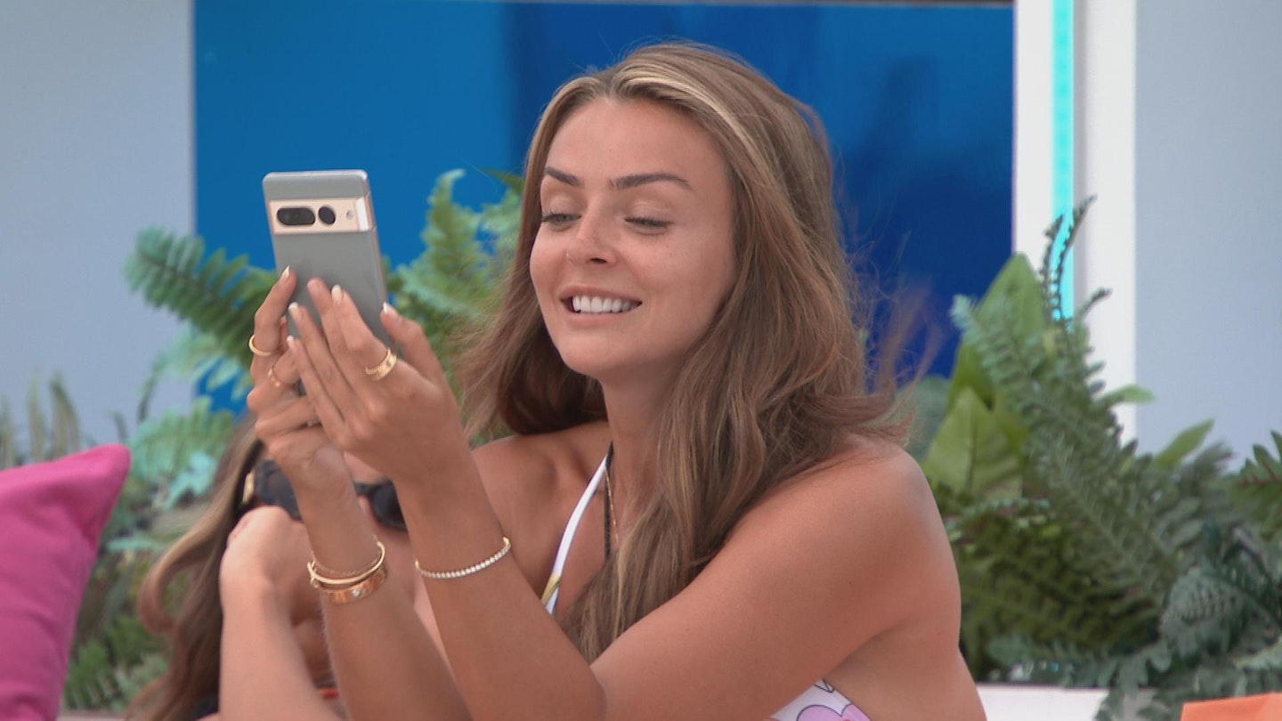 Kady McDermott reading a text from her phone in the Love Island villa