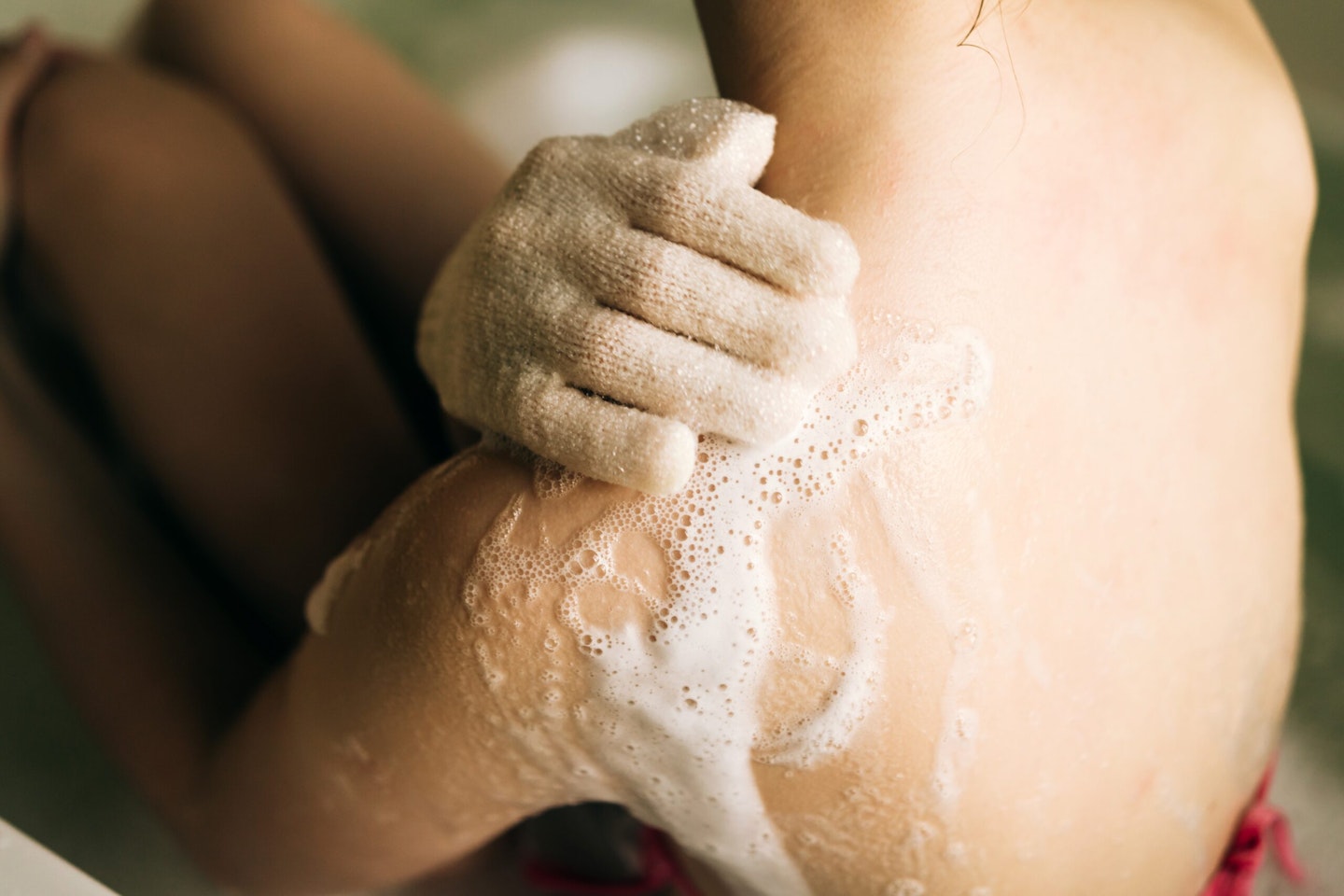 Lady washing skin with a massage glove