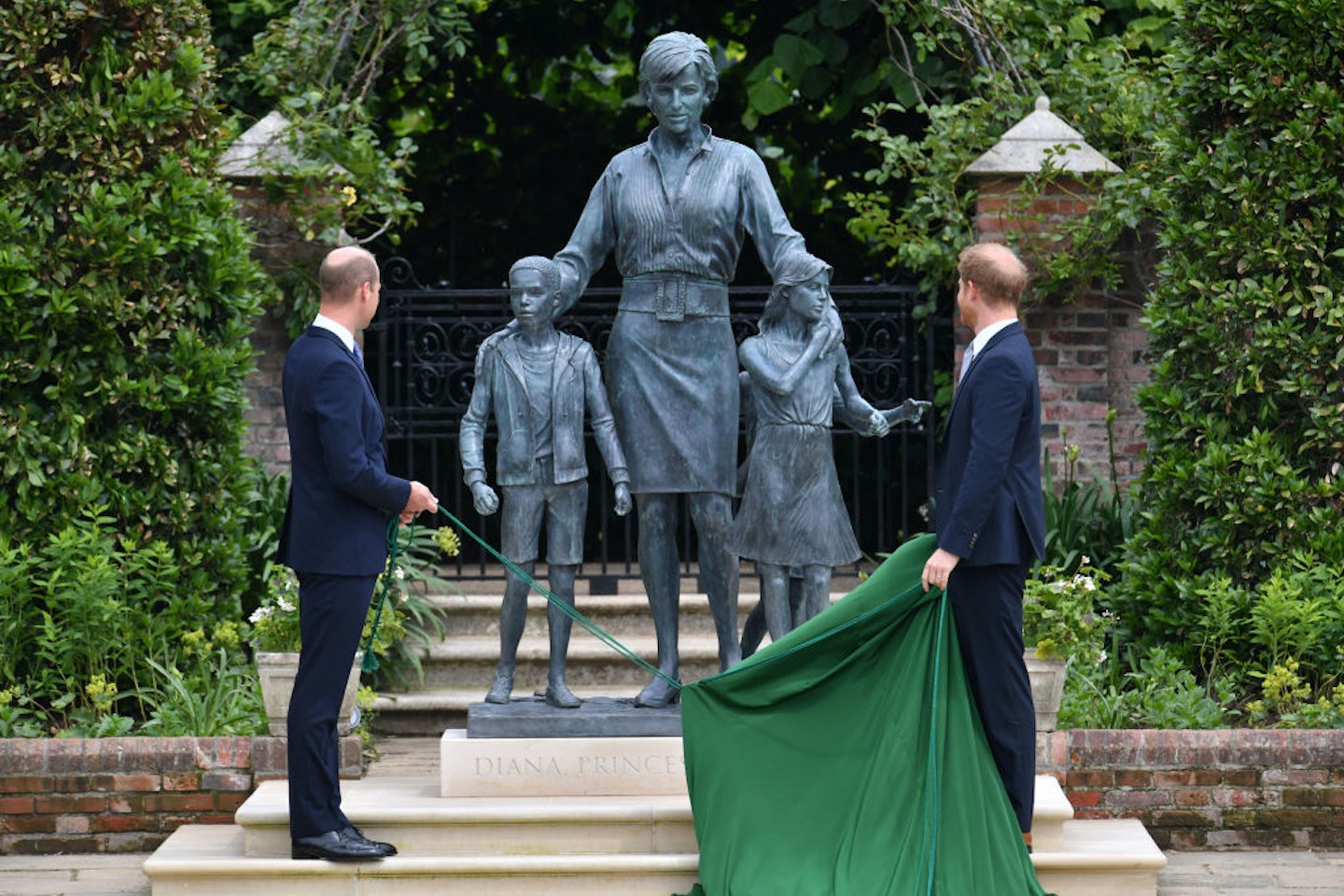Prince William and Prince Harry unveil a statue they commissioned of their mother Diana, Princess of Wales, in the Sunken Garden at Kensington Palace, on what would have been her 60th birthday