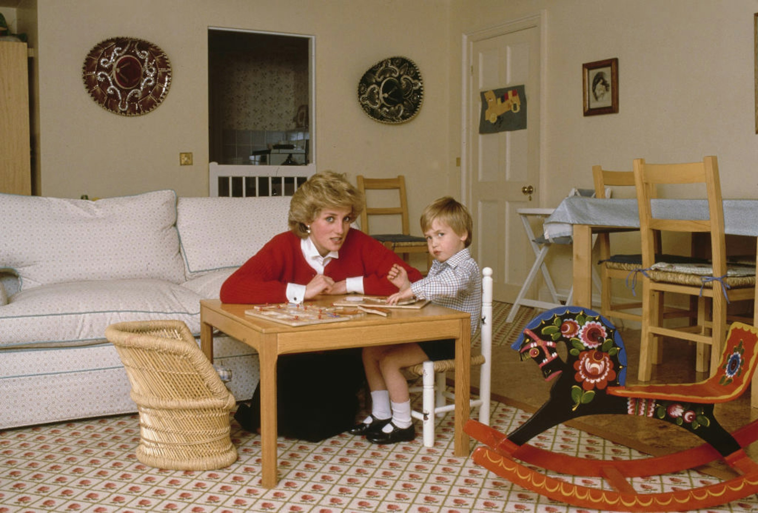 Princess Diana helps toddler Prince William do a puzzle at their home in Kensington Palace, London, England