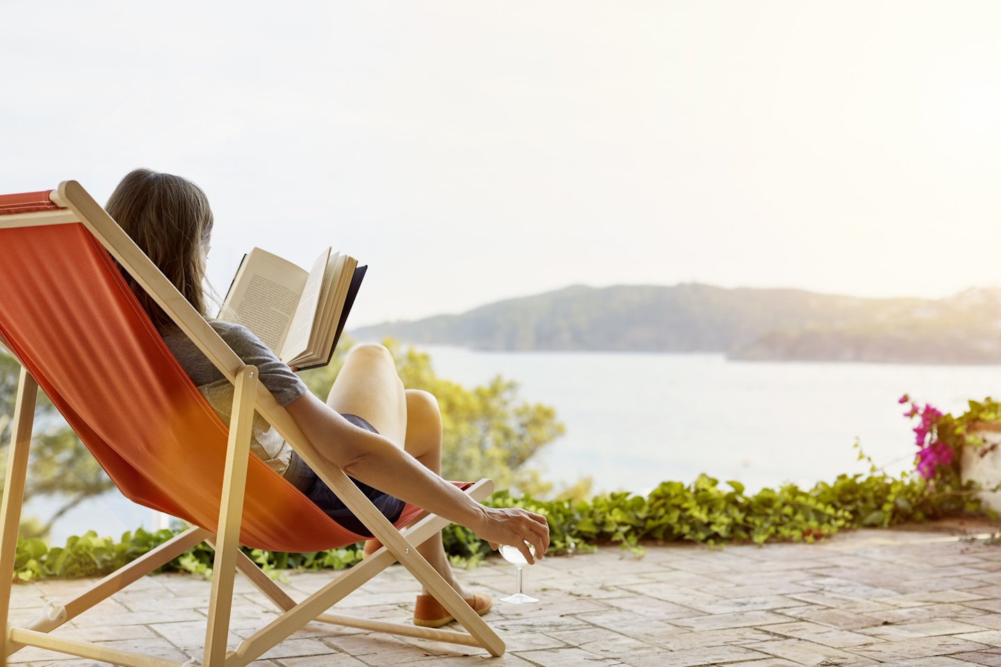 Woman reading book on a deck chair