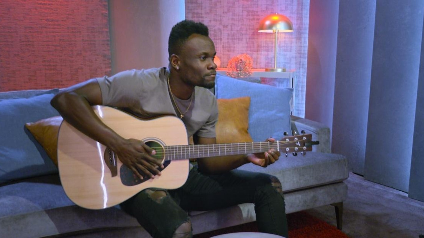Kwame from Love Is Blind season 4 in the pods playing a guitar