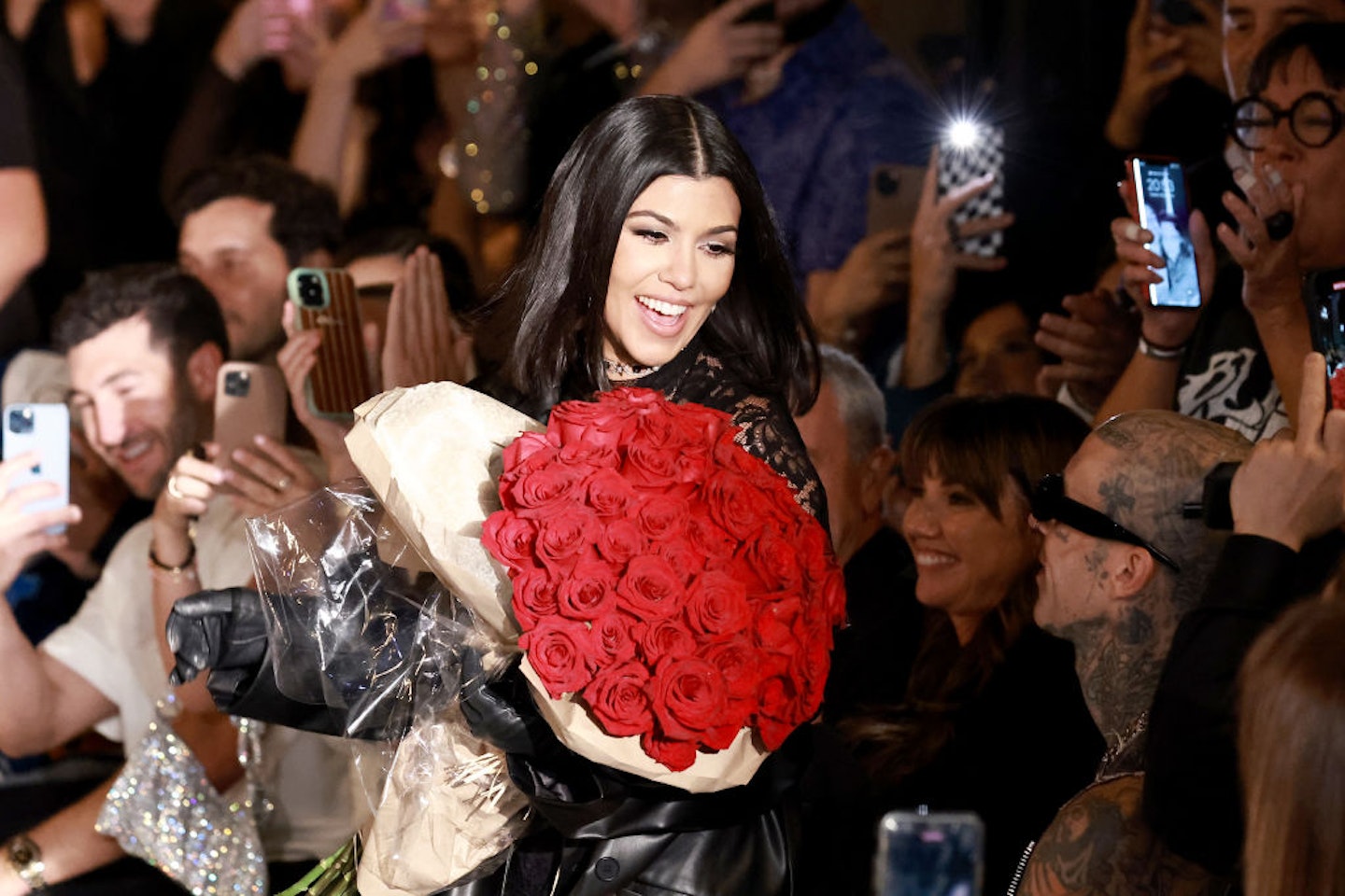 Kourtney holding roses and smiling during her Boohoo fashion show