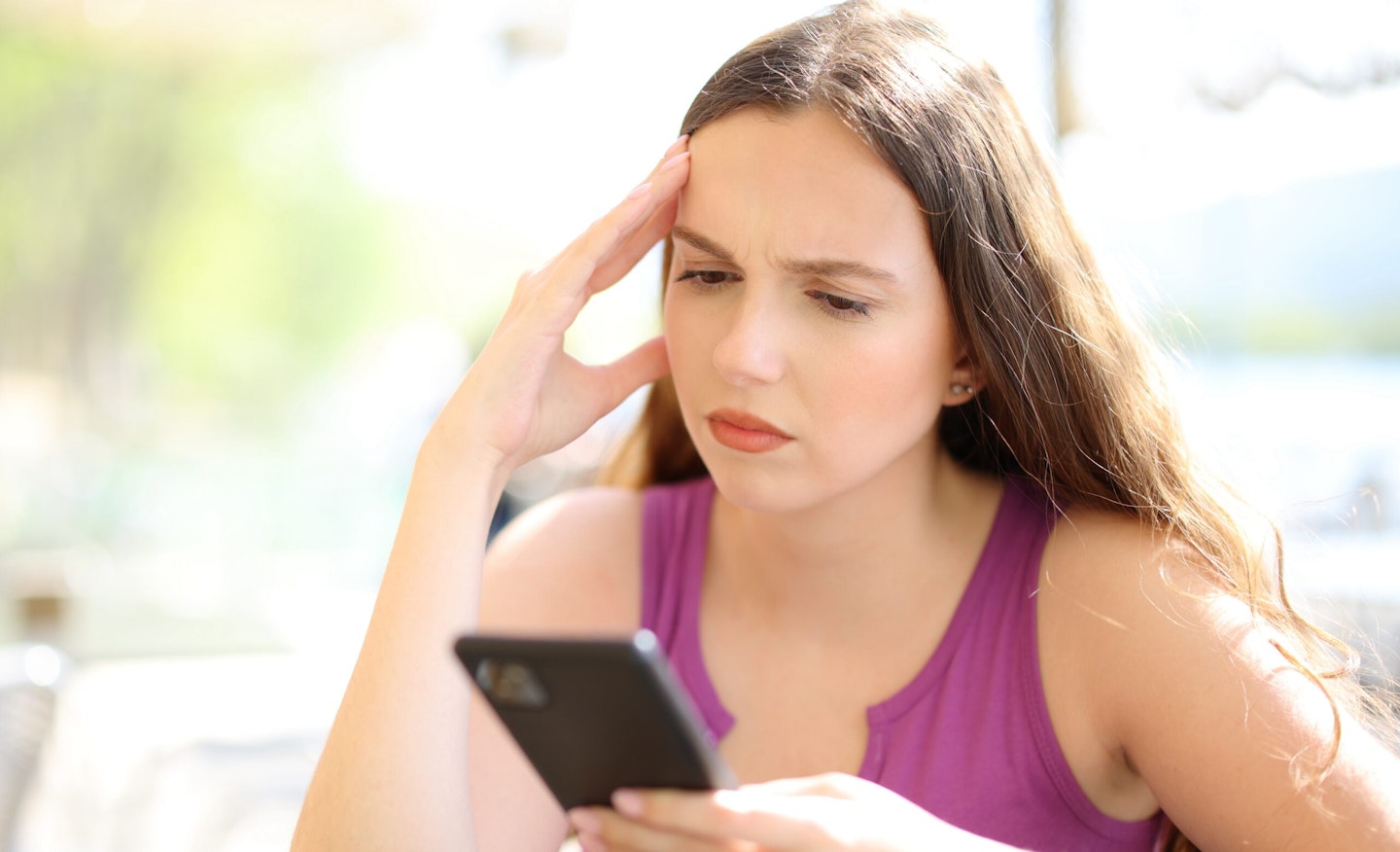 Worried woman checking phone in a bar terrace, Worried woman checking her phone