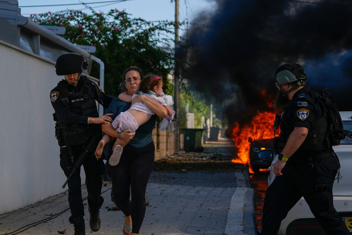 2T0GNDK Police officers evacuate a woman and a child from a site hit by a rocket fired from the Gaza Strip, in Ashkelon, southern Israel, Saturday, Oct. 7, 2023. The rockets were fired as Hamas announced a new operation against Israel. (AP Photo/Tsafrir Abayov)