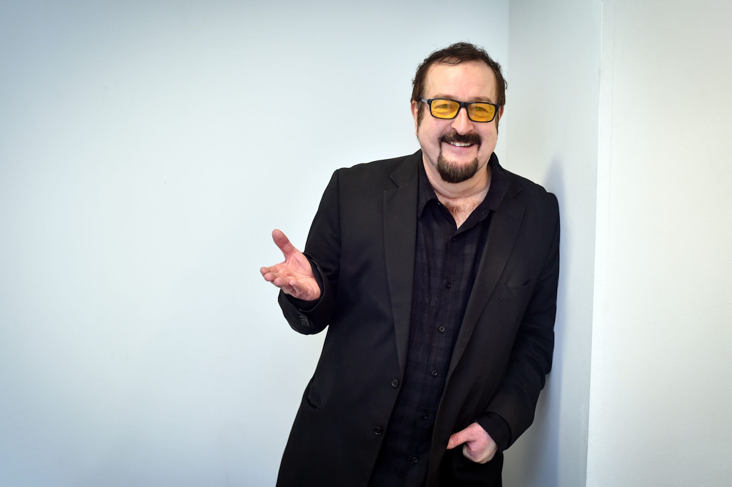 Radio presenter Steve Wright, wearing a black suit, black shirt and yellow-tinted sunglases