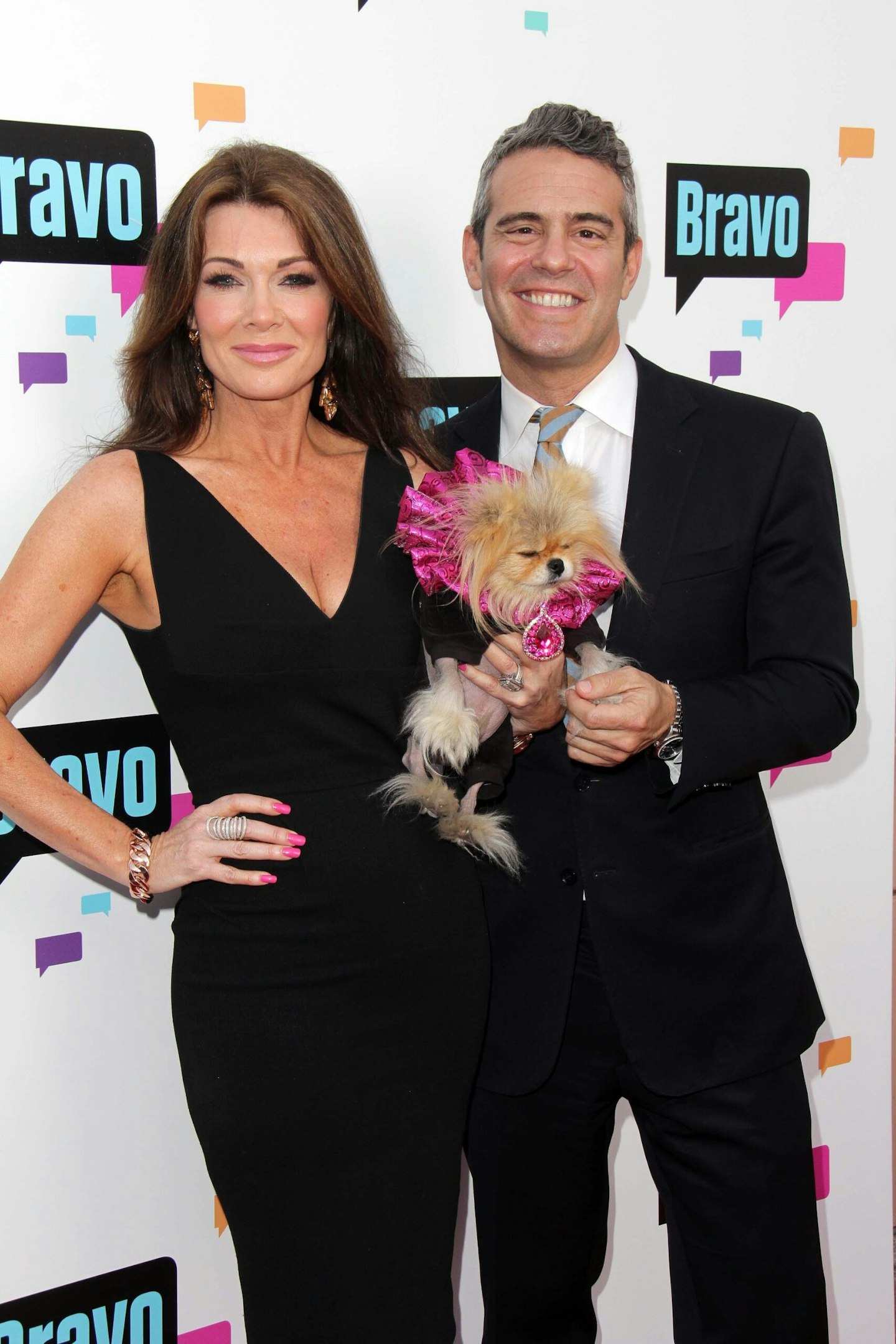 Lisa Vanderpump and Andy Cohen hold a dog on the red carpet