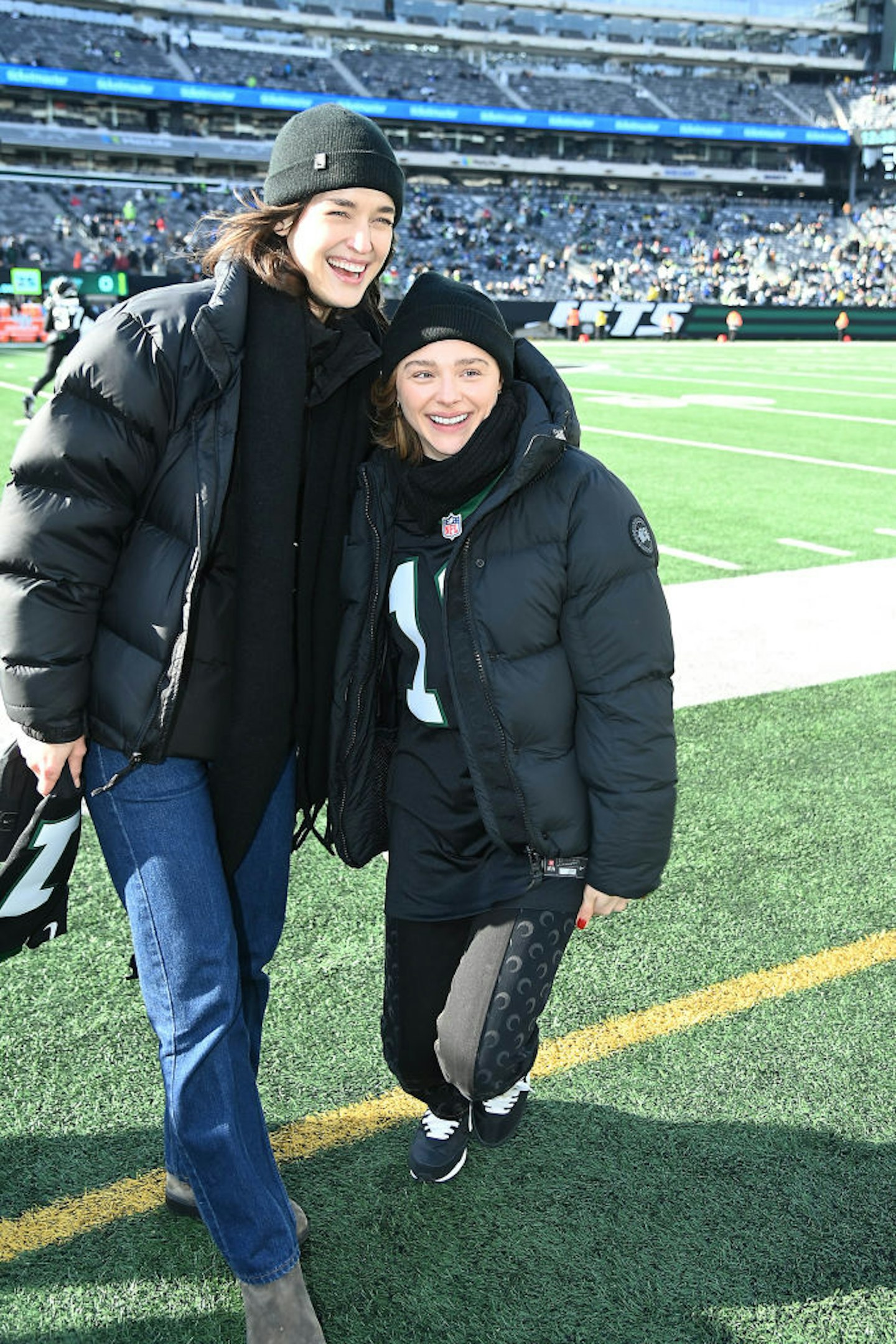Chloe and Kate attend a game together, stood side by side smiling