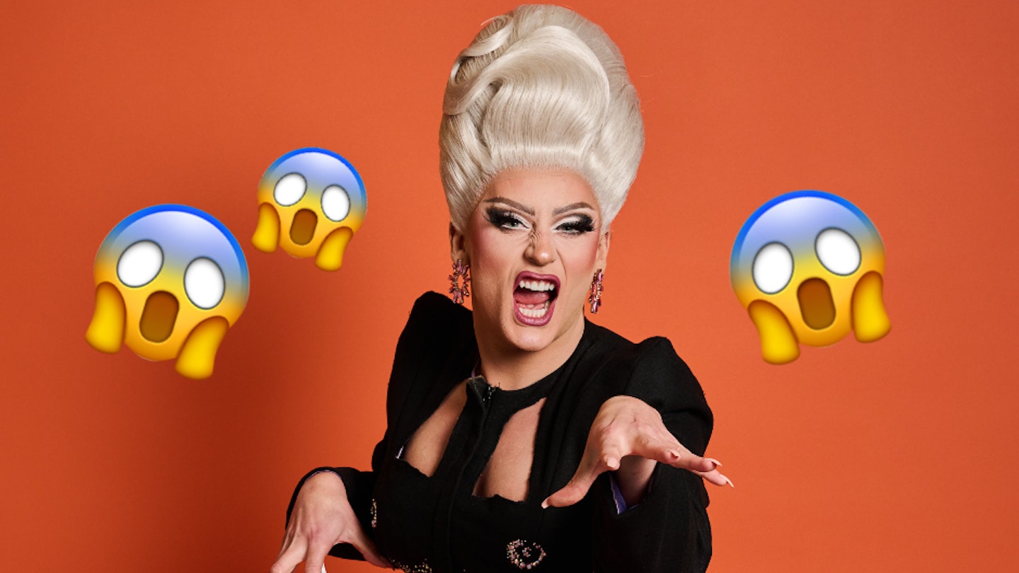 ella vaday growls at the camera in a black dress and blonde wig in front of an orange background