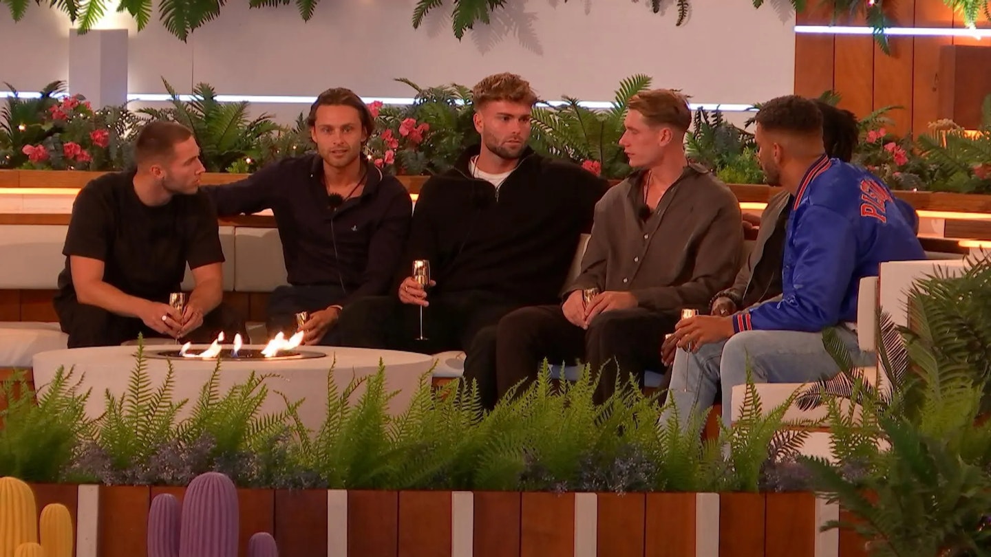 Love Island boys sitting around the fire pit