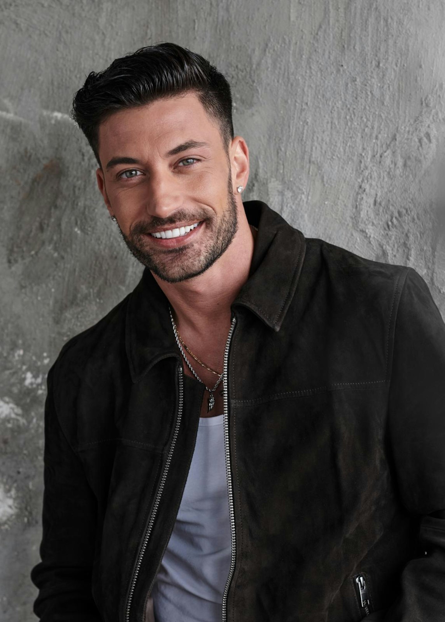 Giovanni Pernice smiles as he wears a black jacket and grey t-shirt