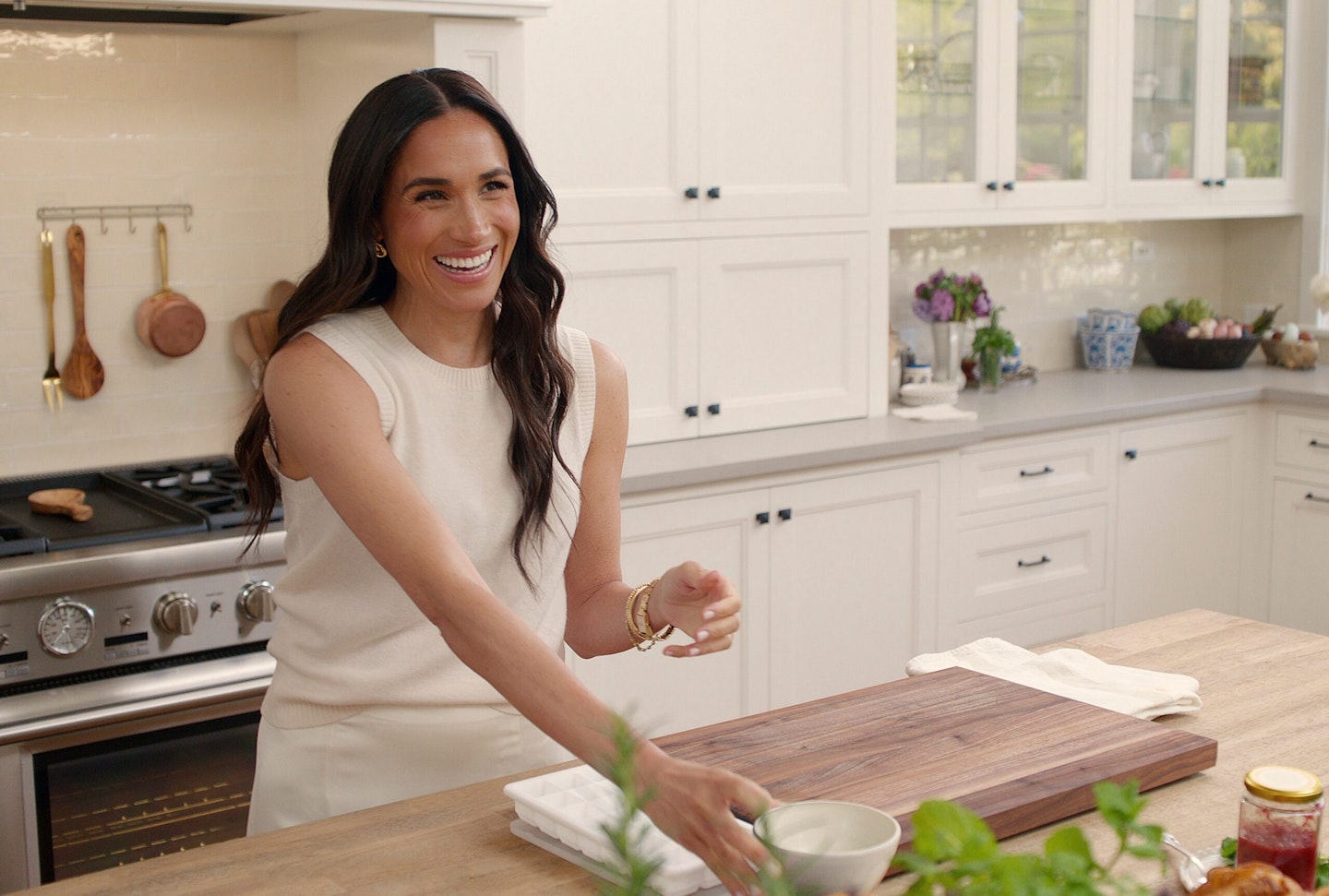 Meghan Markle smiles in the kitchen wearing a white dress