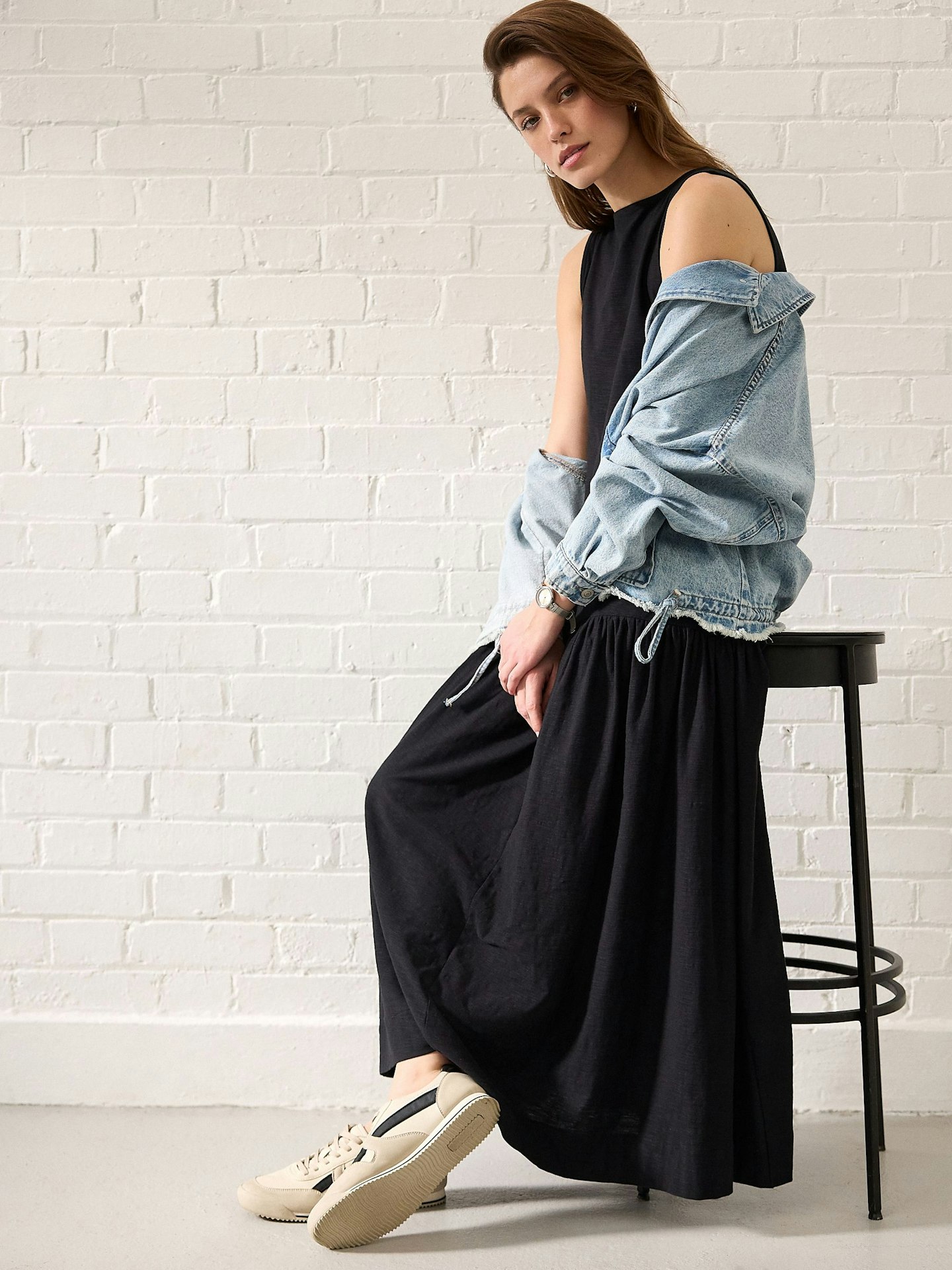 Model wearing a black Next midi dress and a denim jacket