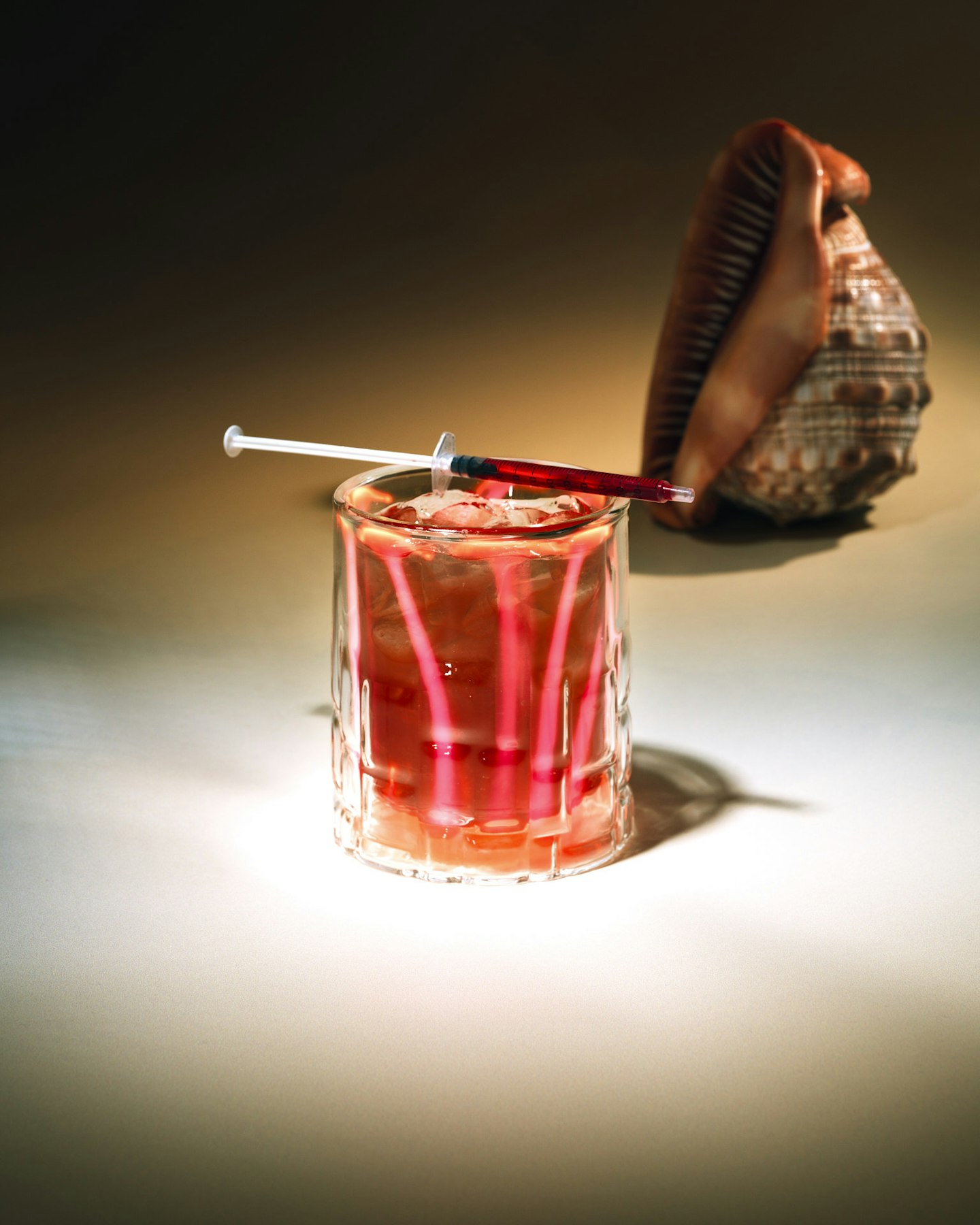 red cocktail with a syringe on top