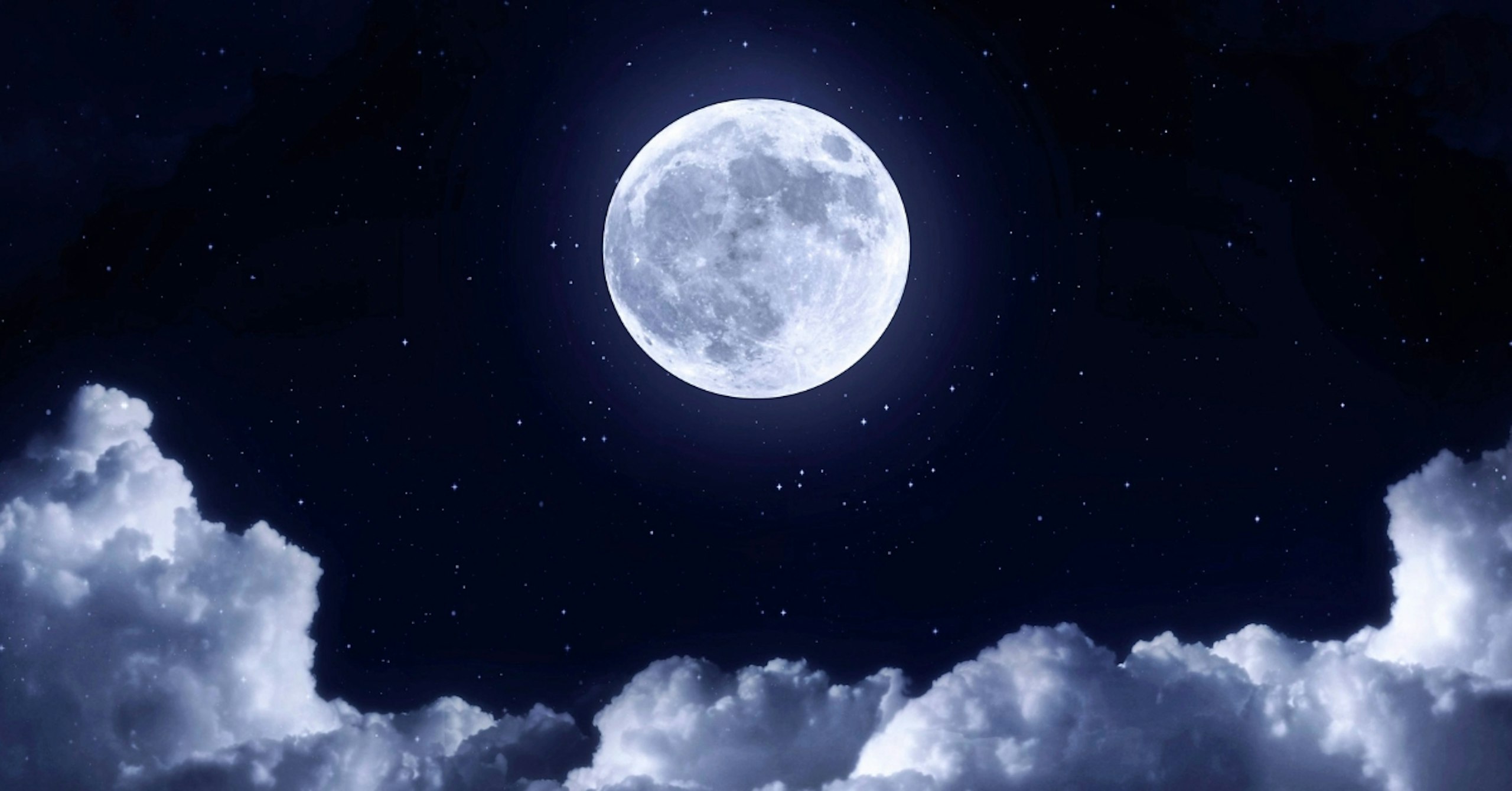 Full moon shining above clouds in a star-filled night sky