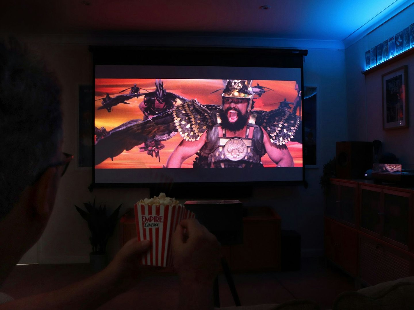 Author sitting with popcorn in a living room with Flash Gordon on the Valerion VisionMaster Pro 2 4K Laser Projector