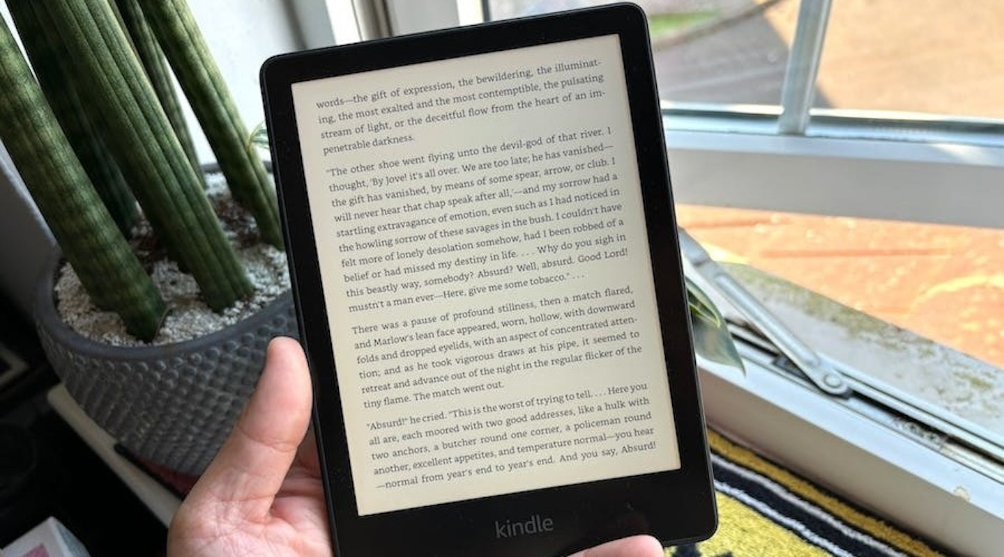 Kindle Paperwhite held in hand in front of window and plant. Best tech gifts.