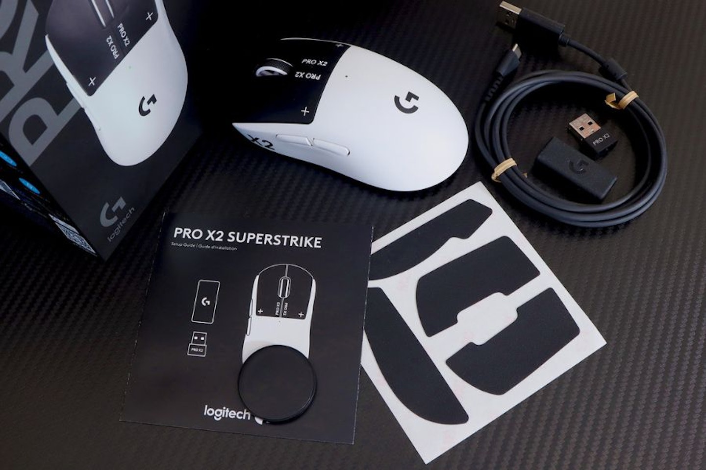 Logitech PRO X2 SUPERSTRIKE Gaming Mouse, box and accessories on a gaming desk