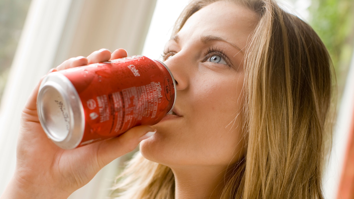 Woman drinks from can of coke