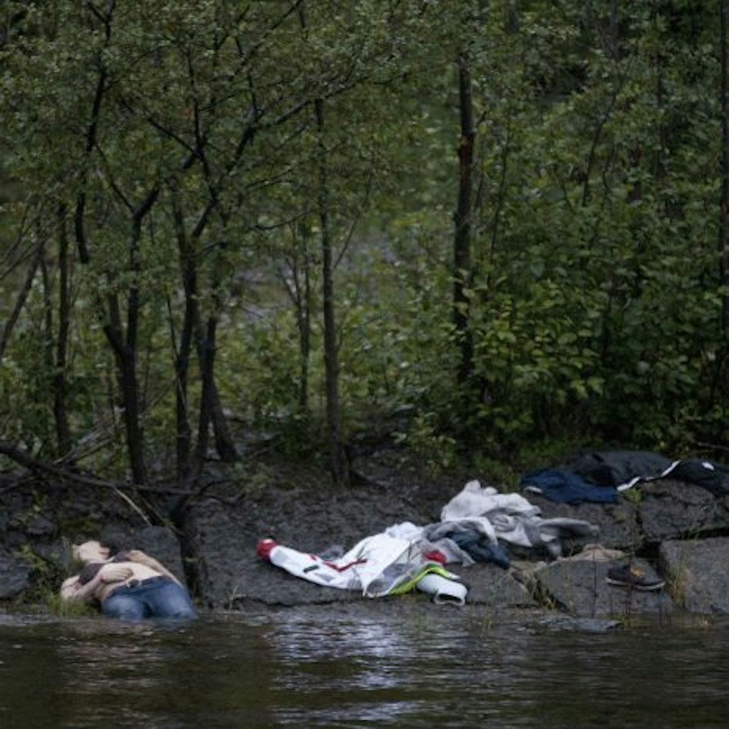 A body and victim's clothes can be seen close to the water after the attacks on the Norweigan island