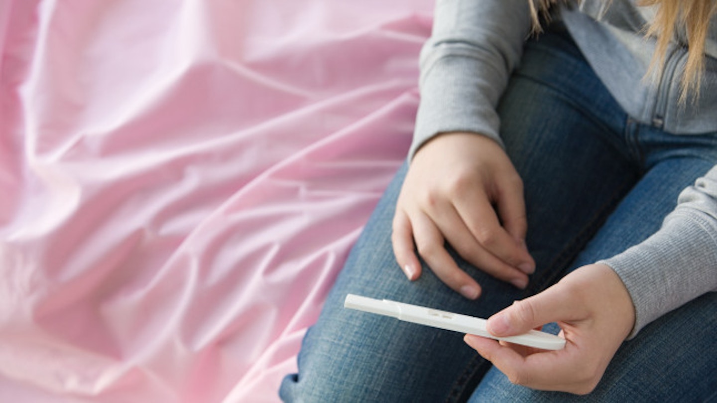 Stock image of a young girl looking at a pregnancy test