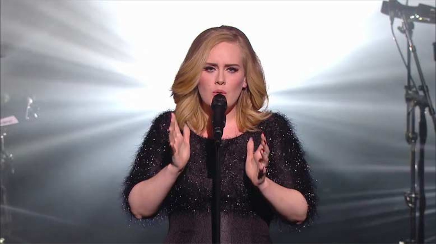 Adele singing on stage in a black dress at The Grammy Awards