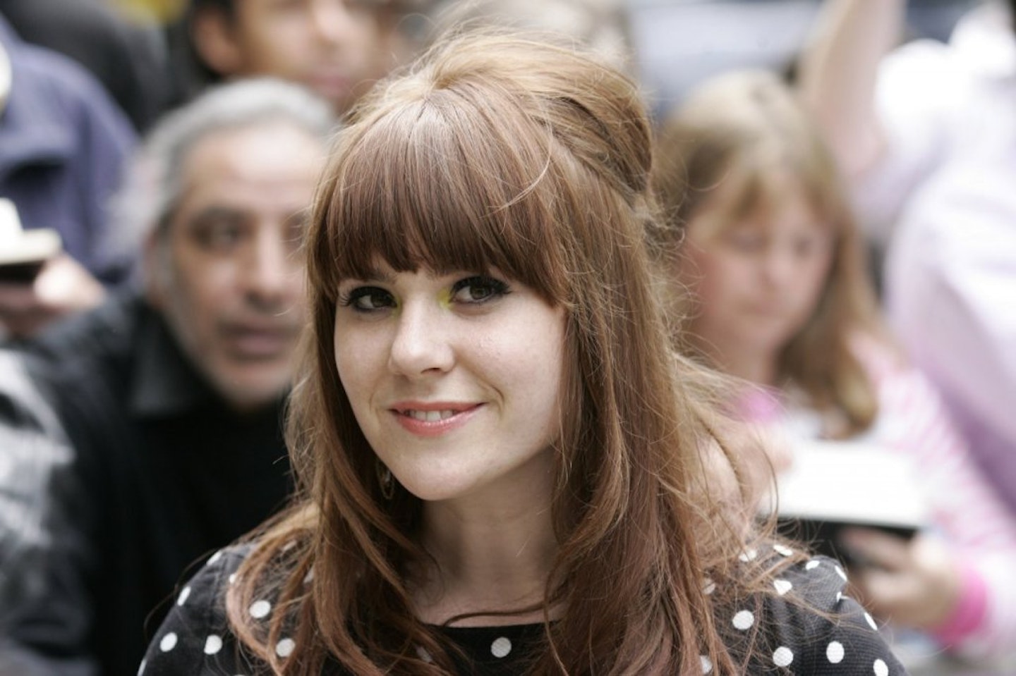 Kate Nash posing for photo in a black polka dot blouse