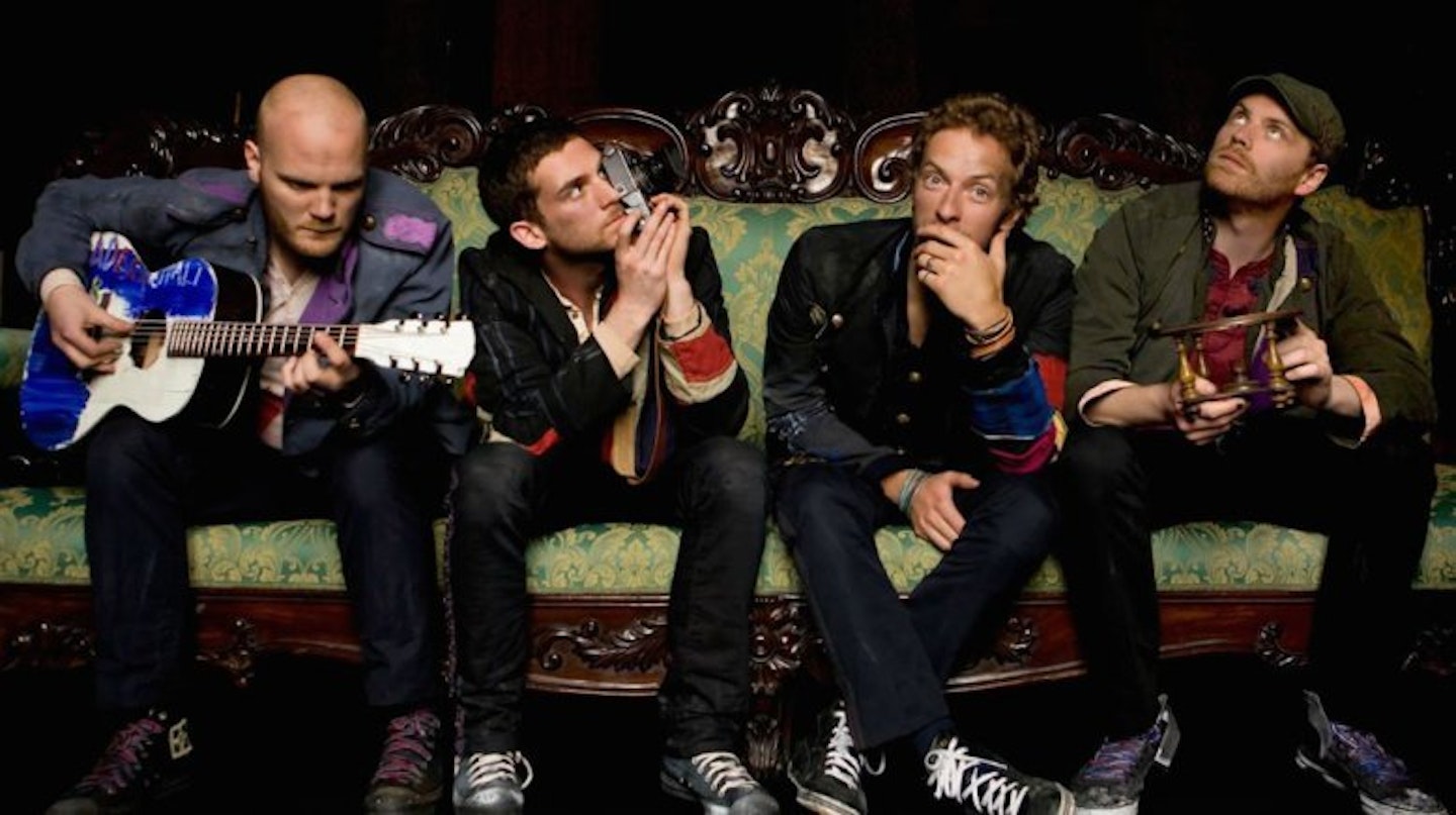Coldplay sit on a green couch