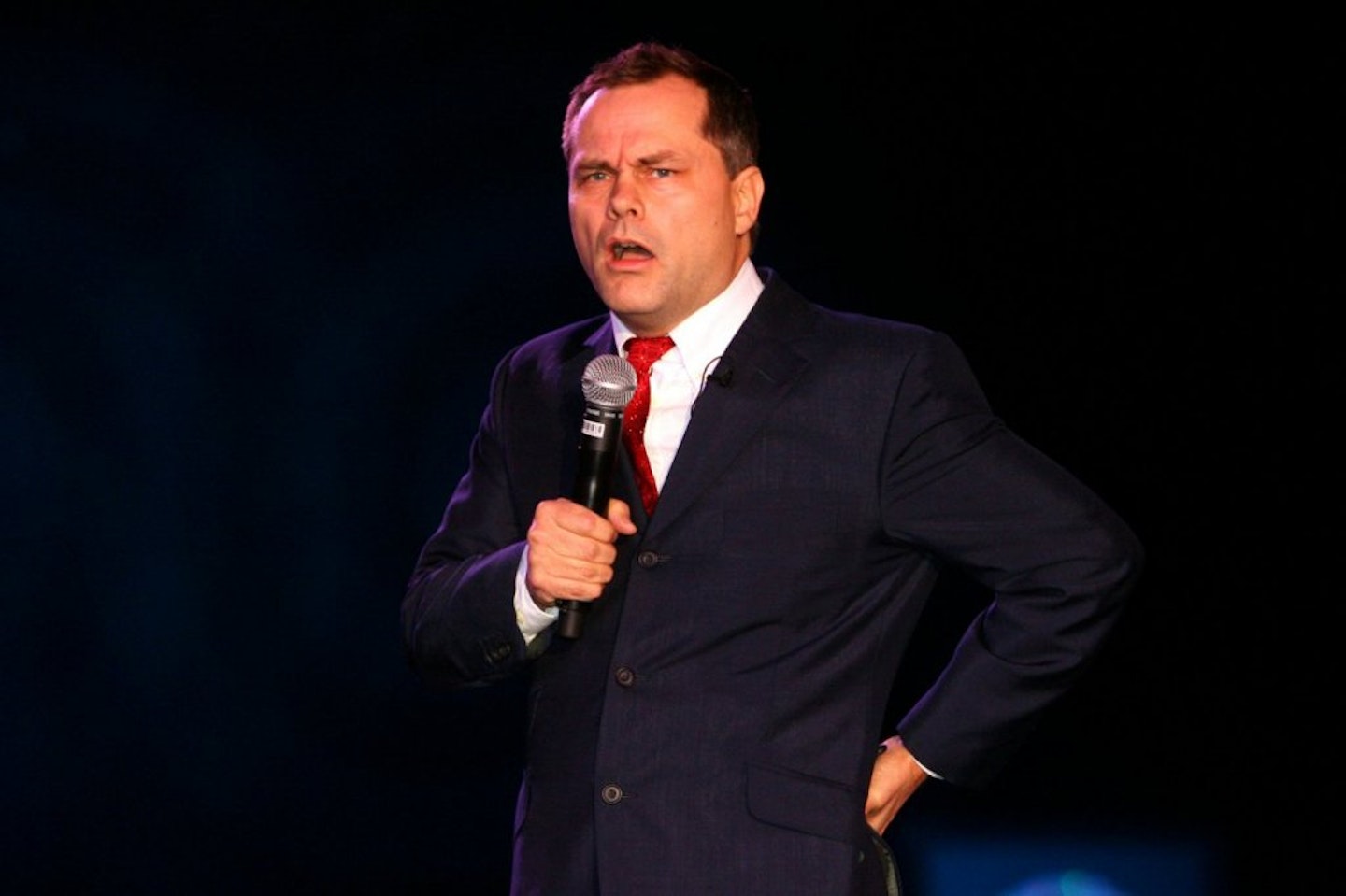 Jack Dee on stage talking into a microphone