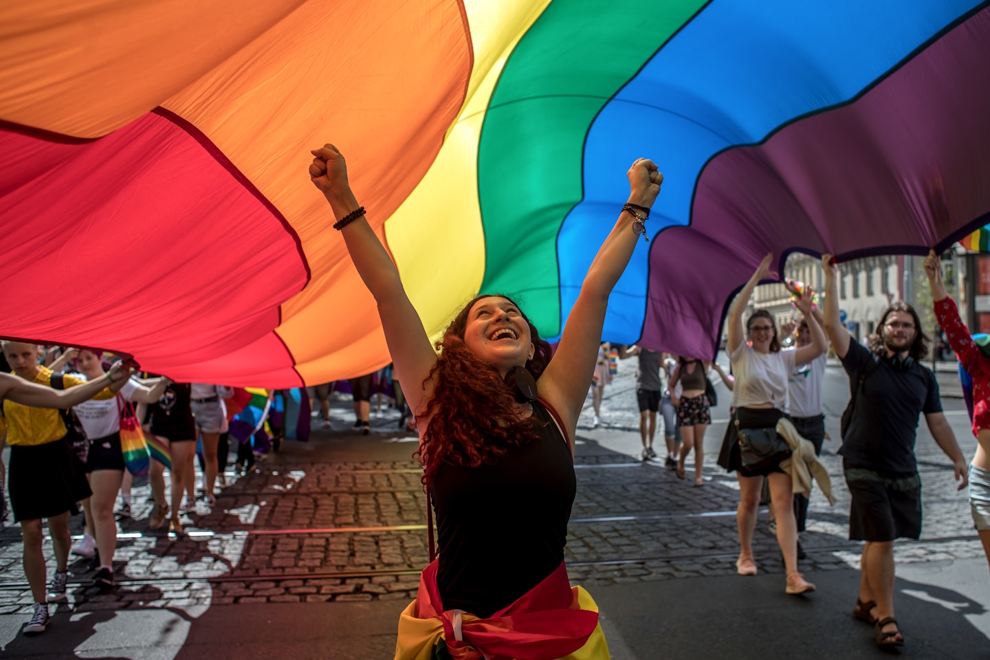 A woman walking under a rainbow flag