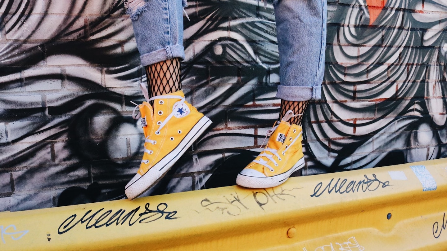 Woman's legs in yellow converse on metal barrier