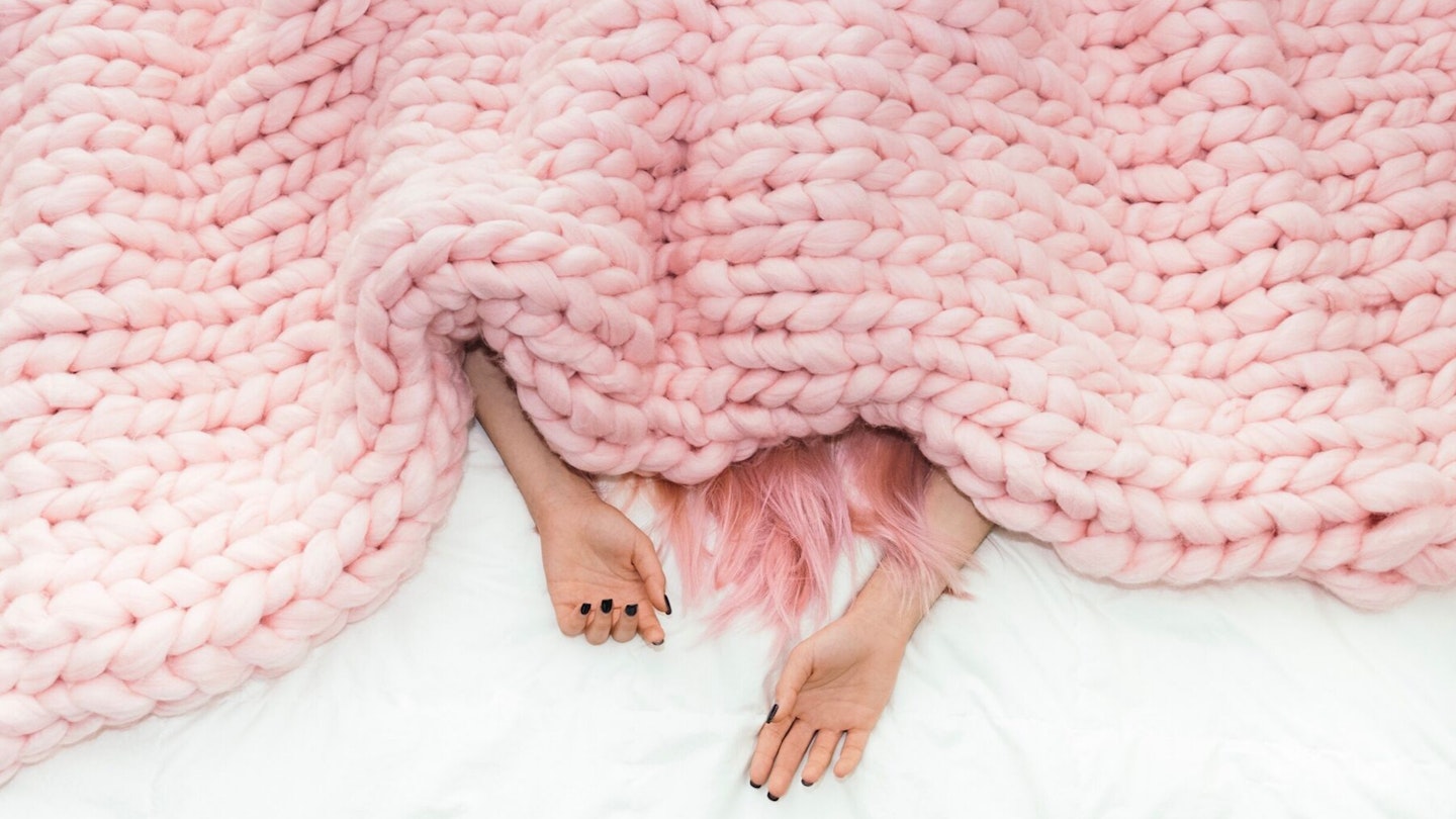 Woman under pink knitted blanket