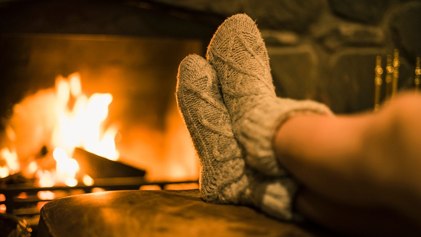 Woman's legs with cosy socks in front of fire