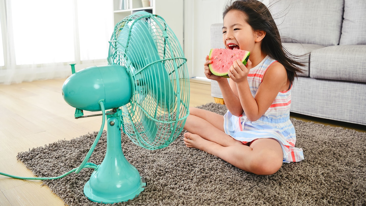 Girl eating watermelon in front of a stylish fan