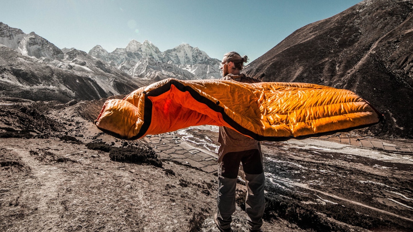 A man waving around a down sleeping bag near Everest