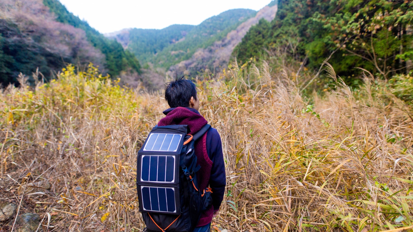 Man walking into wilderness with solar cells on his backpack