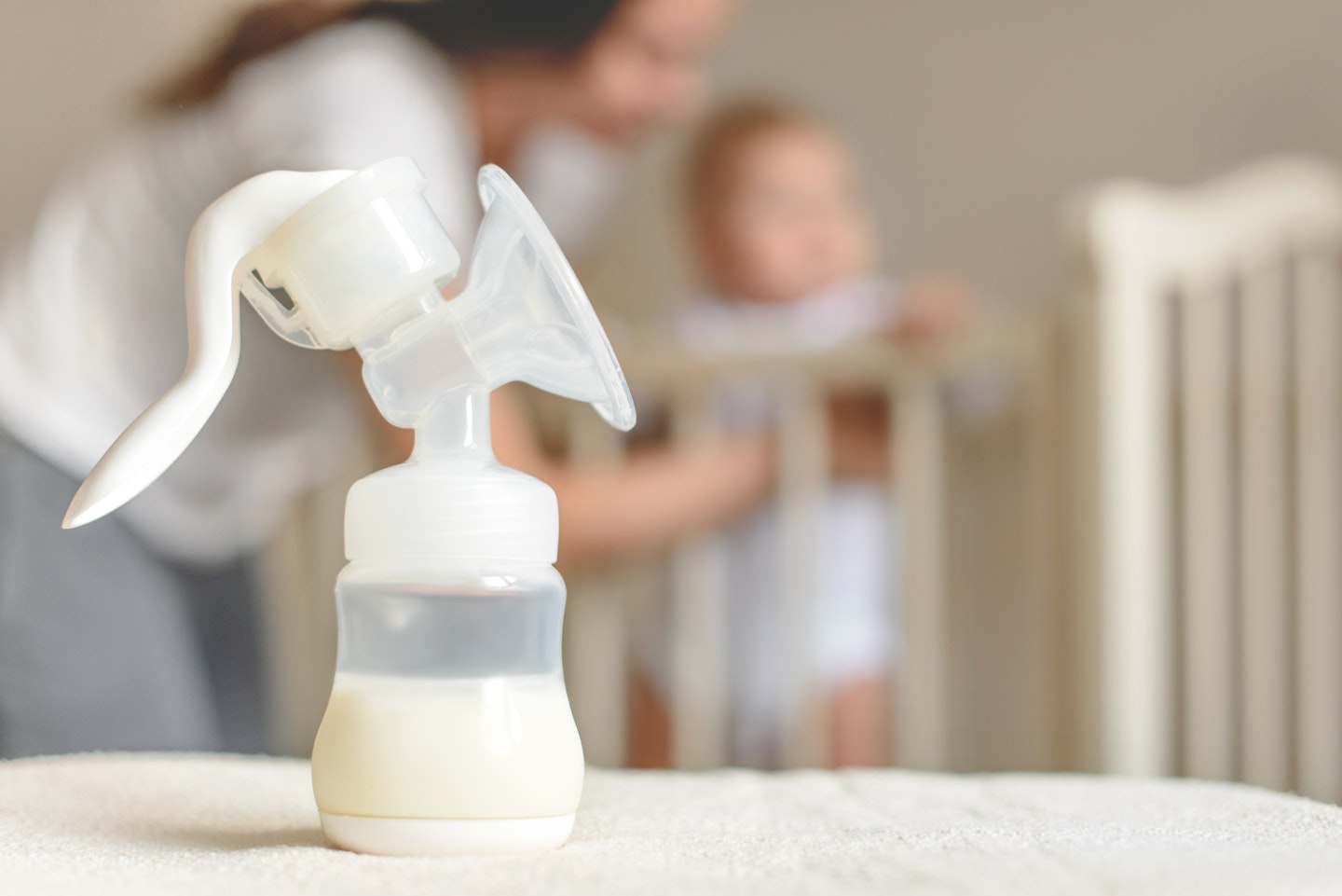 Breast pump on table with mother and baby in background