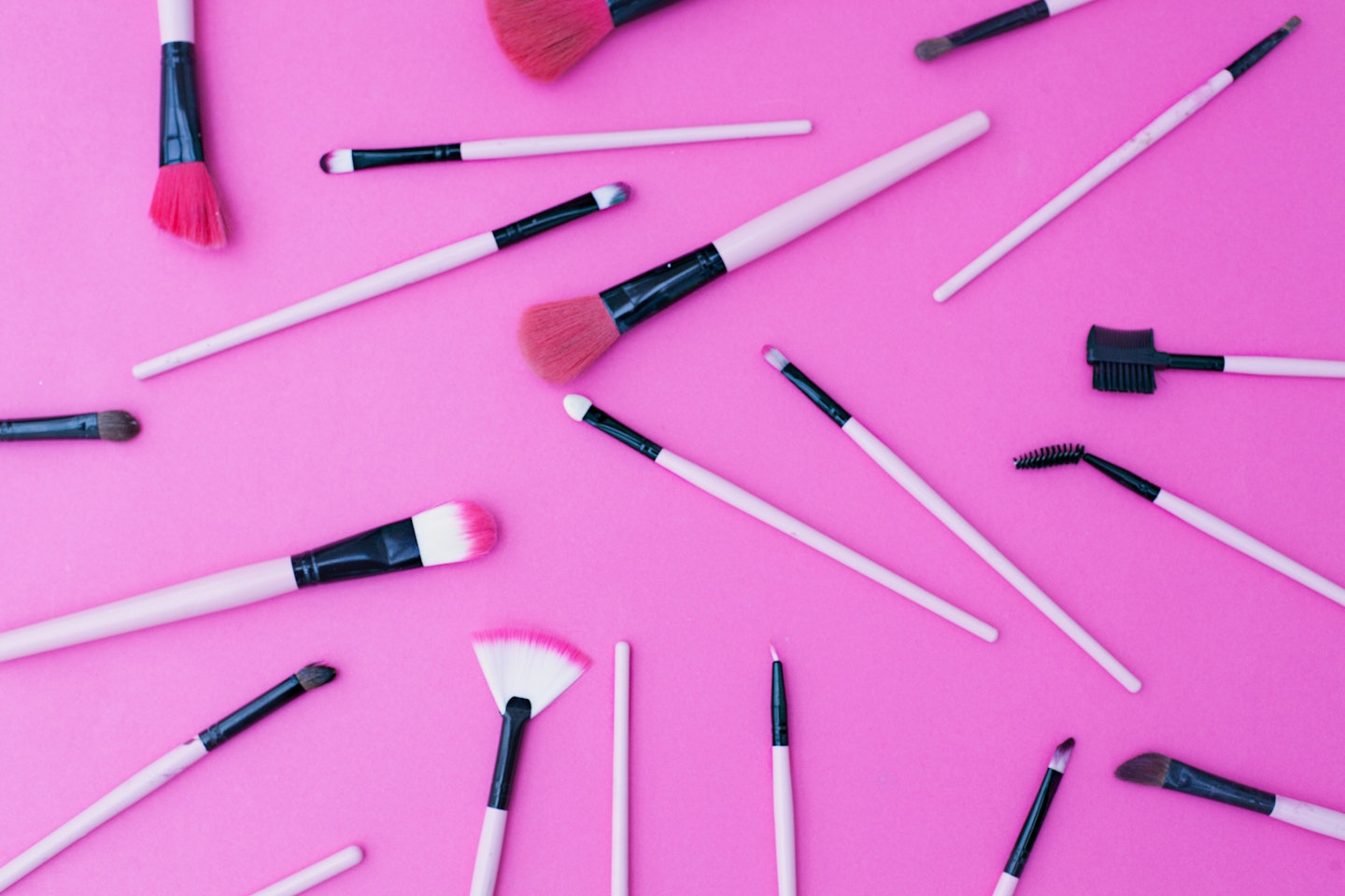 Makeup brushes on a pink background